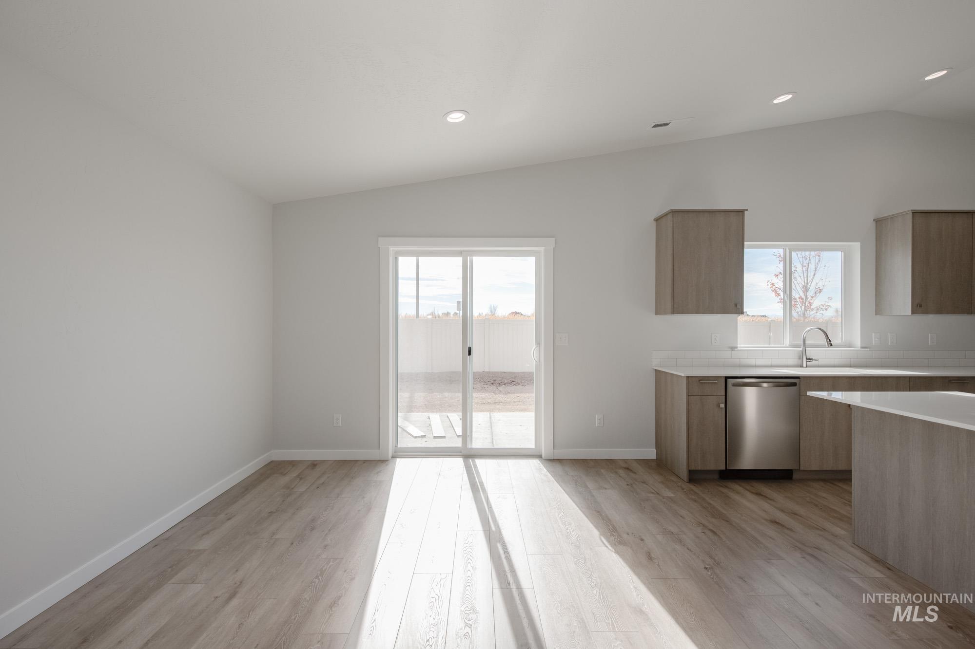 Kitchen featuring lofted ceiling, modern cabinets, healthy amount of natural light, stainless steel dishwasher, and recessed lighting