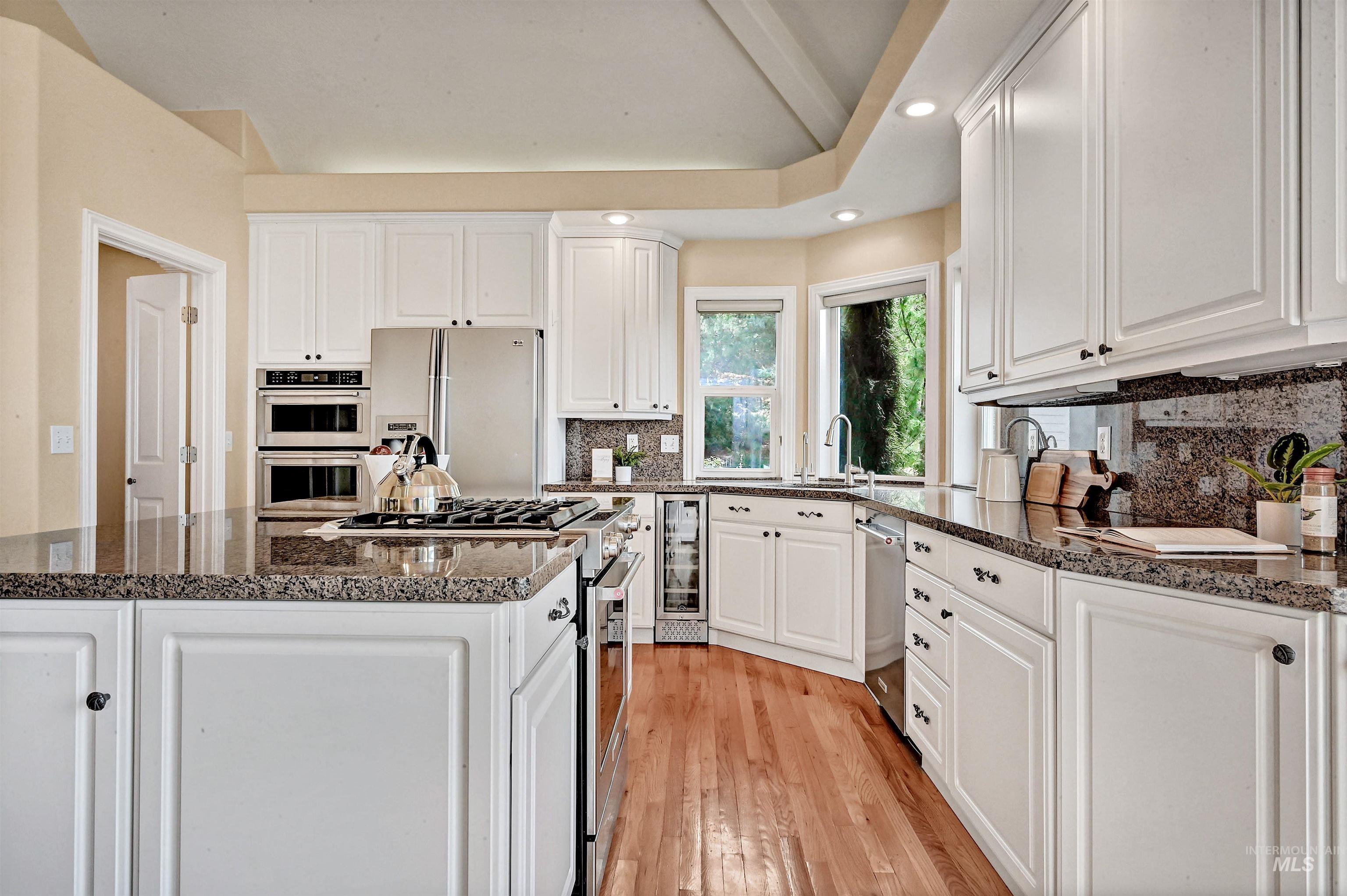 Kitchen with recessed lighting, white cabinets, stainless steel appliances, decorative backsplash, and light wood-type flooring