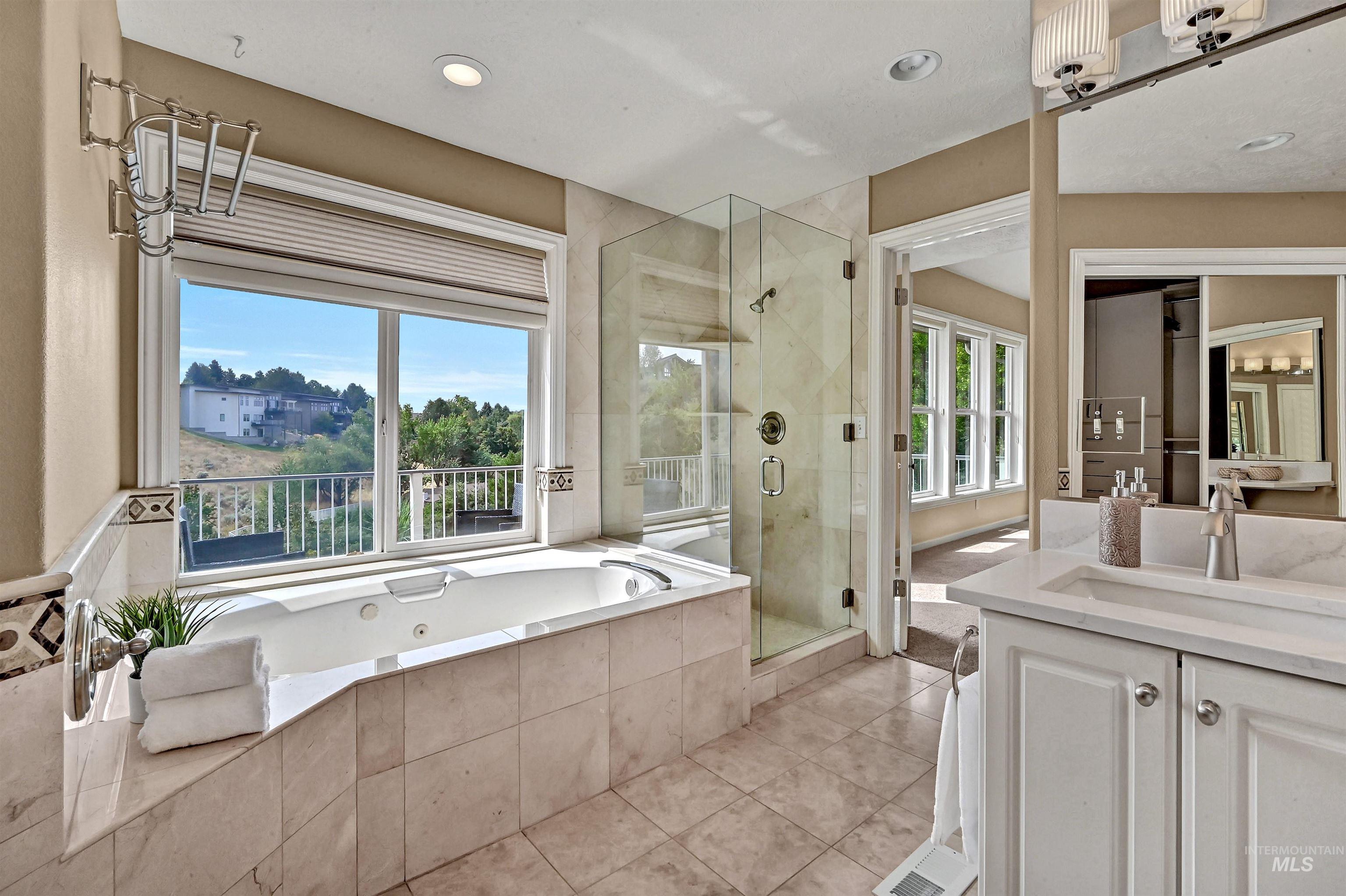 Bathroom with a shower stall, vanity, a bath, light tile patterned flooring, and recessed lighting