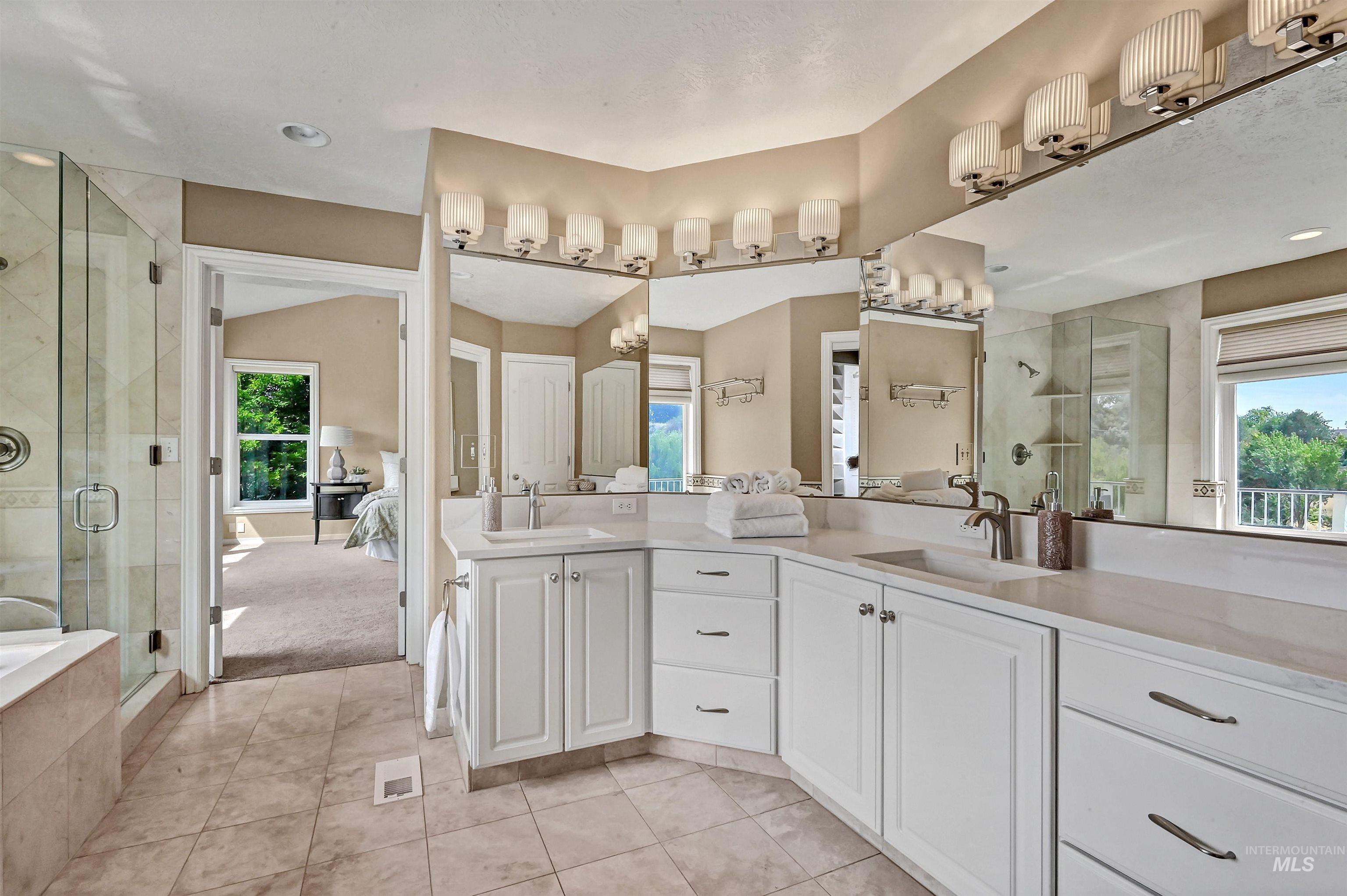 Ensuite bathroom featuring double vanity, a stall shower, light tile patterned floors, and recessed lighting