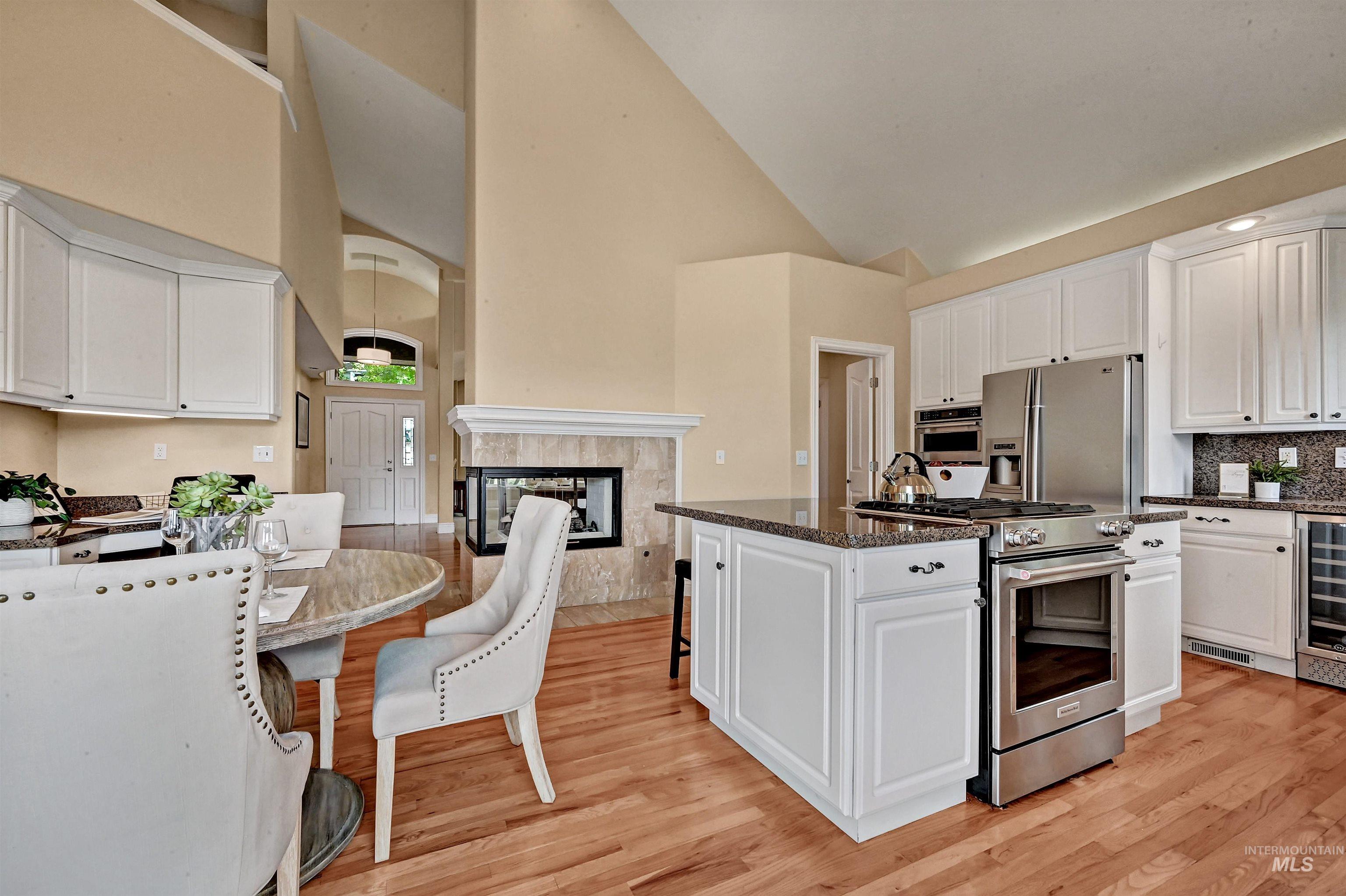 Kitchen with white cabinetry, high vaulted ceiling, appliances with stainless steel finishes, a breakfast bar area, and light wood-style flooring
