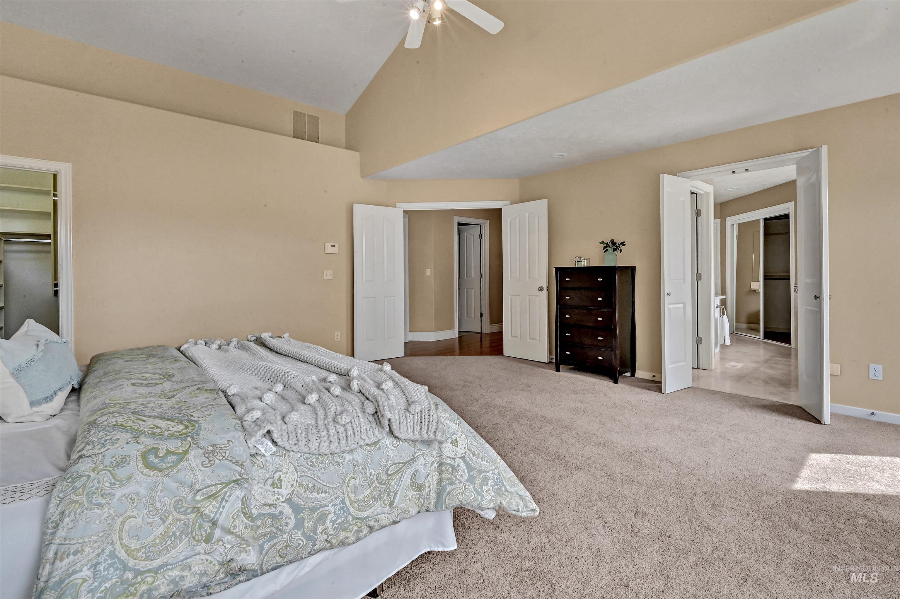 Carpeted bedroom featuring ceiling fan and high vaulted ceiling