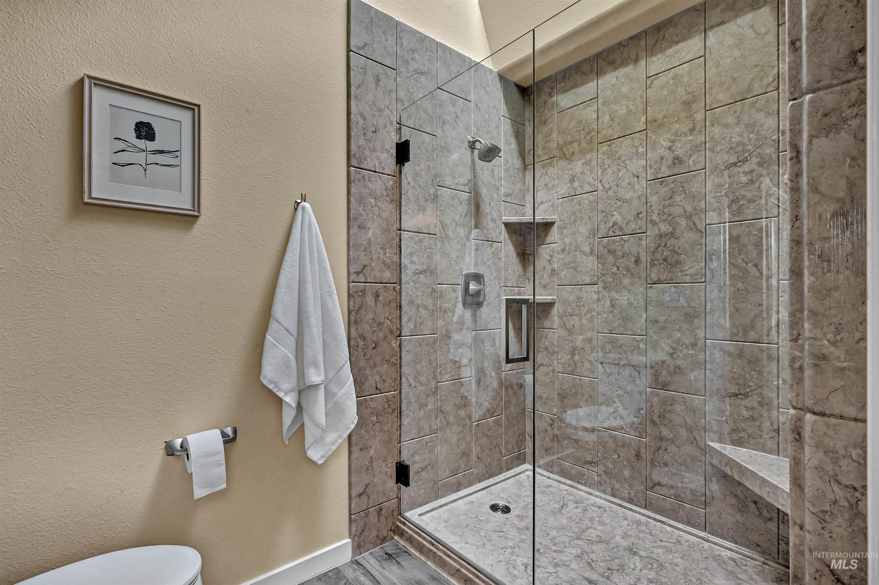 Bathroom featuring a textured wall and a stall shower
