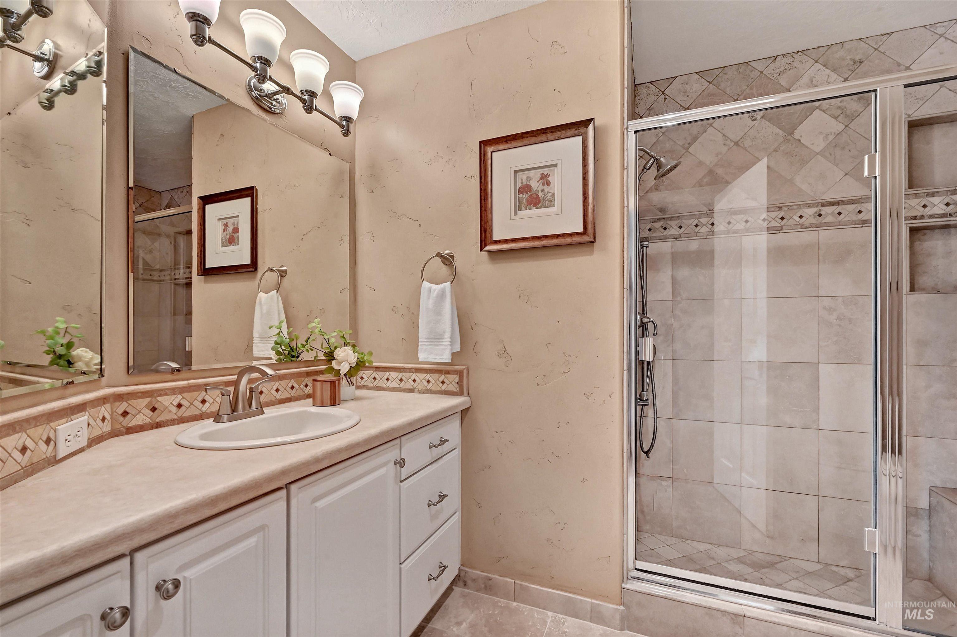 Bathroom with vanity, a stall shower, light tile patterned floors, and decorative backsplash