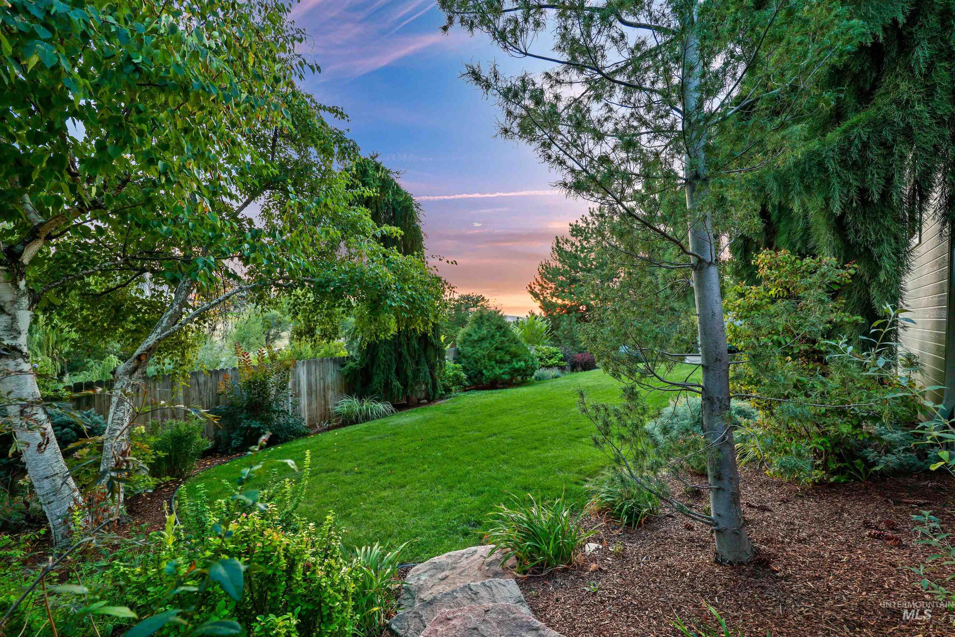 Yard at dusk with view of wooded area