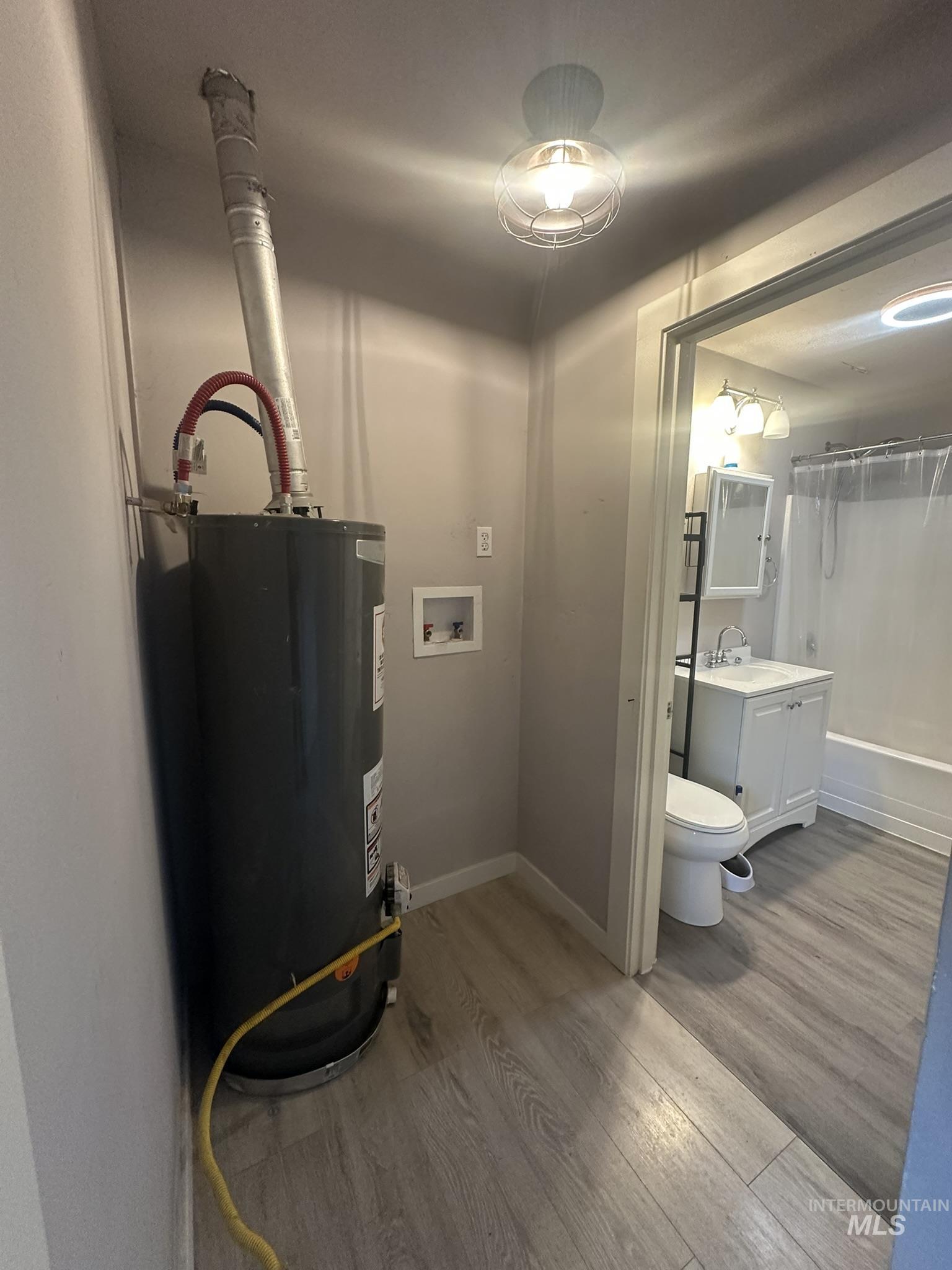 Utility room featuring gas water heater and a sink