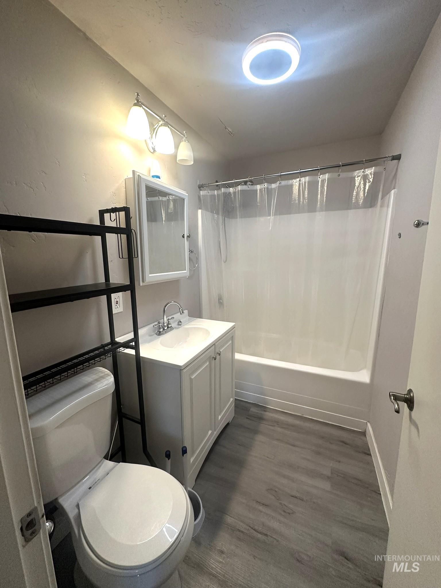 Bathroom featuring vanity, shower / bath combo, and dark wood finished floors