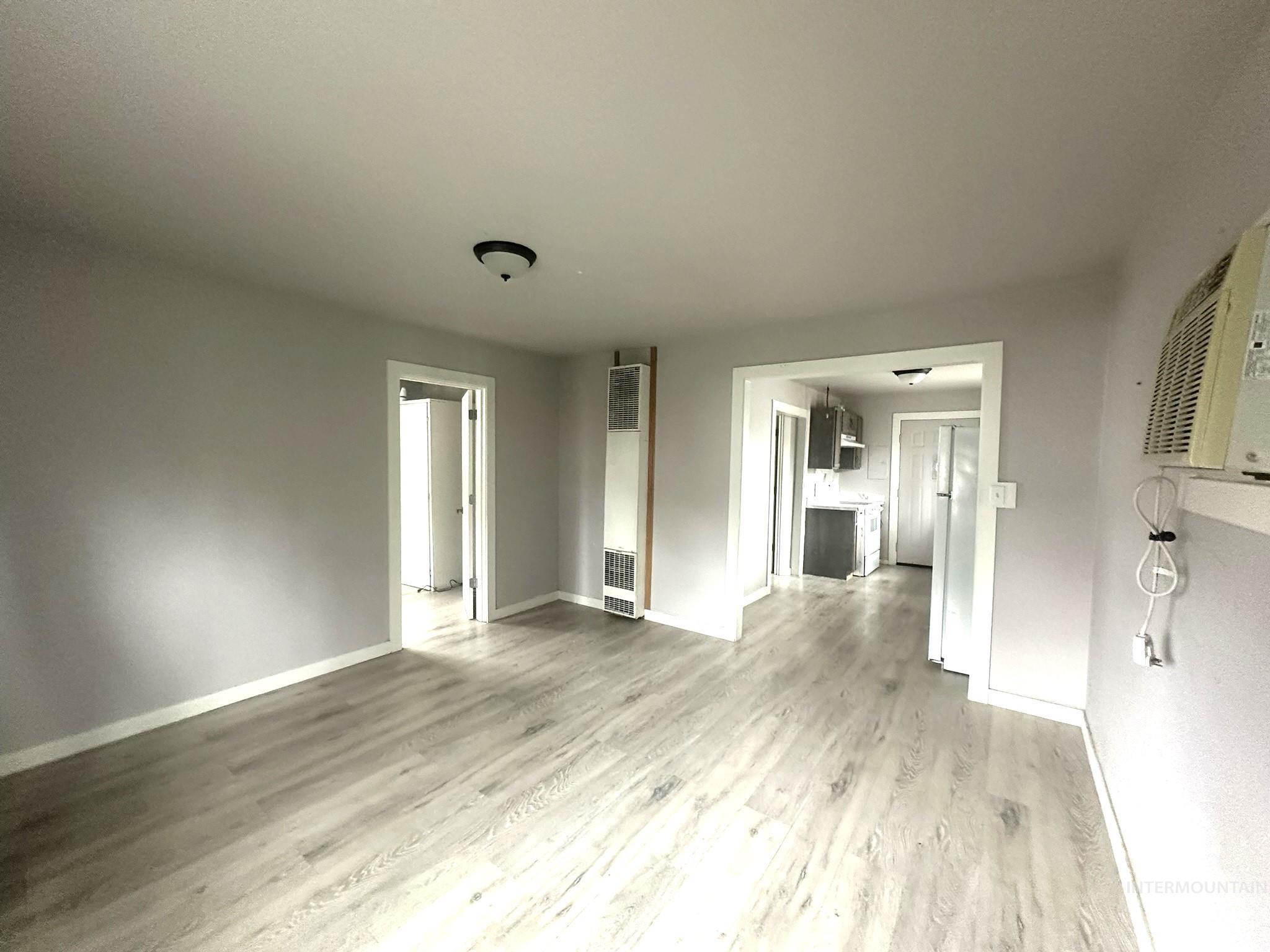 Unfurnished living room featuring light wood-style flooring and a heating unit