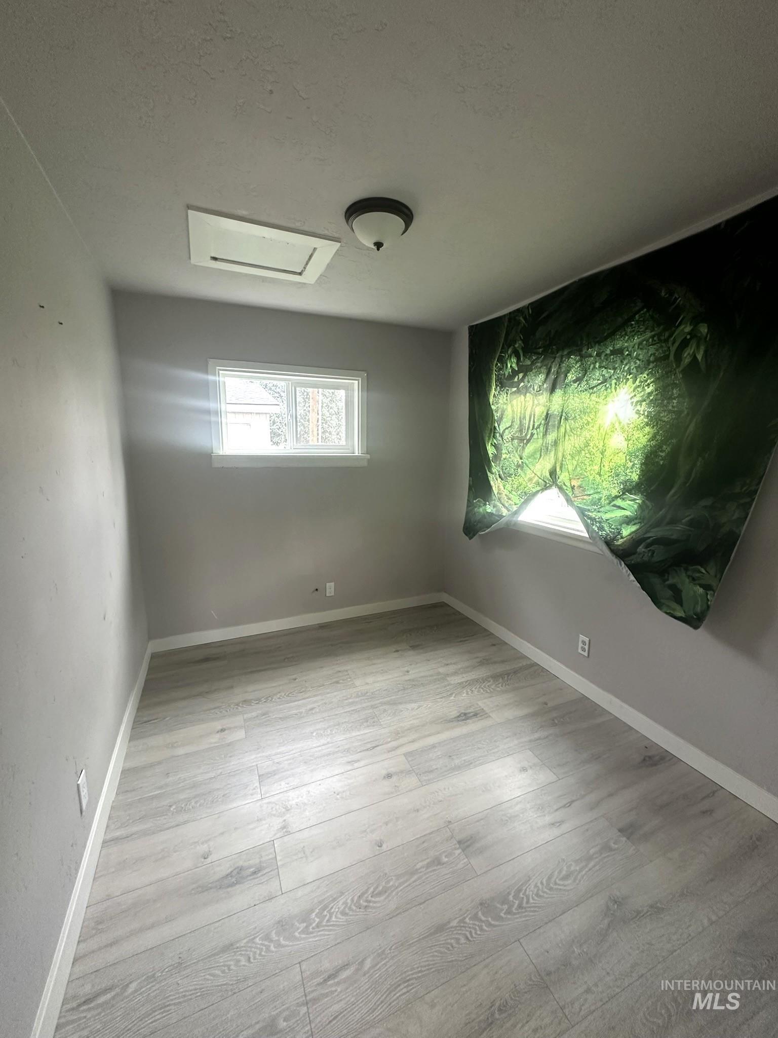 Unfurnished room featuring a textured ceiling and light wood-type flooring