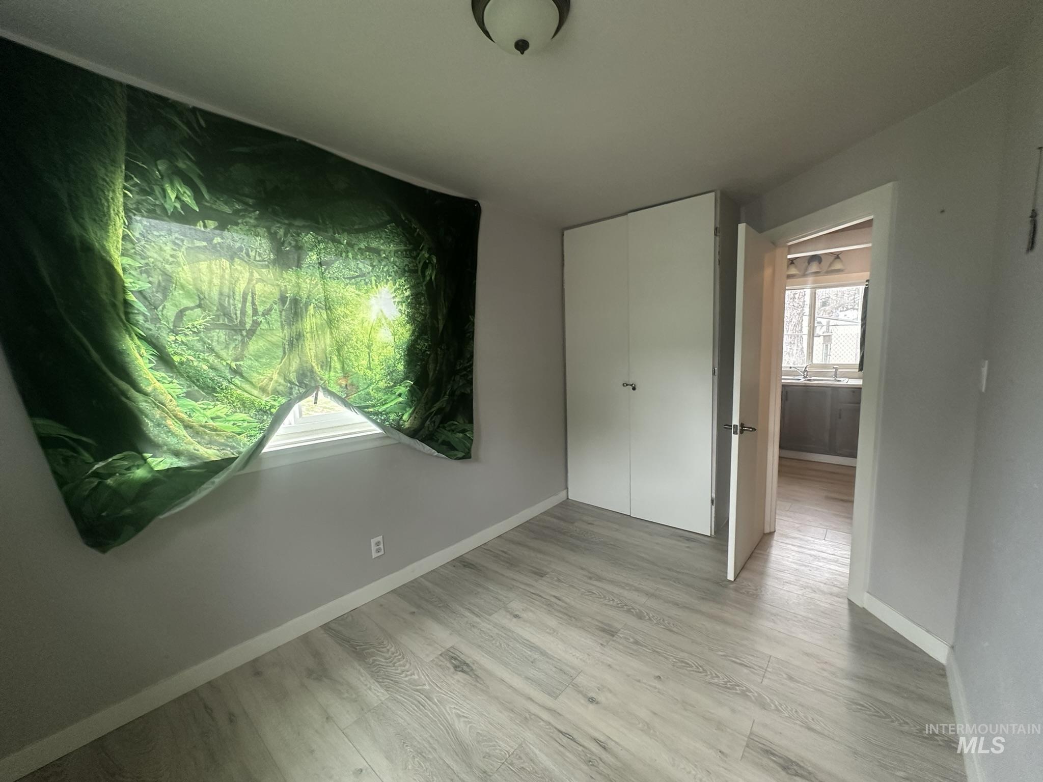 Unfurnished bedroom featuring light wood-type flooring and a closet
