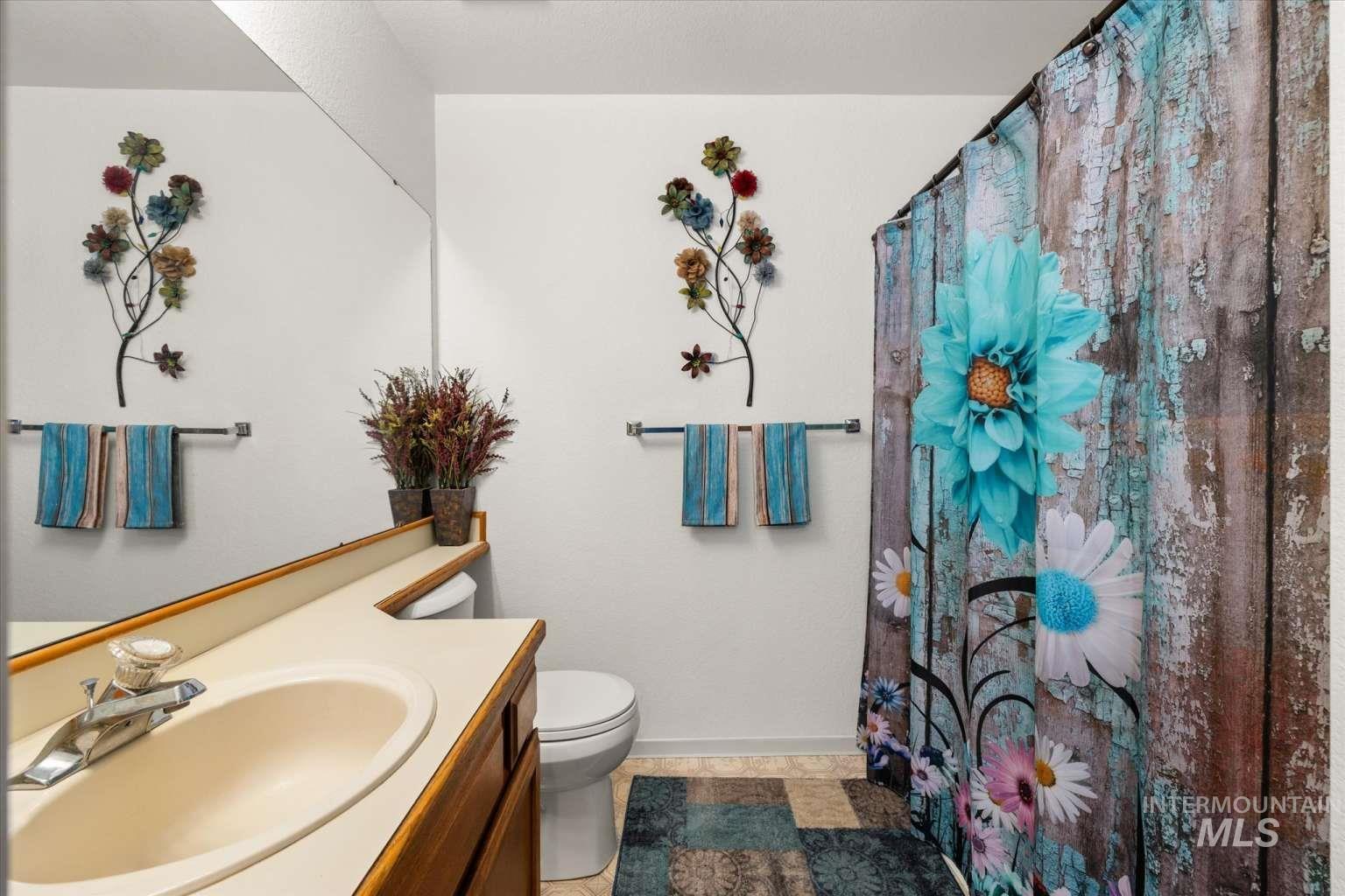 Full bathroom with vanity, light tile patterned floors, and a shower with curtain
