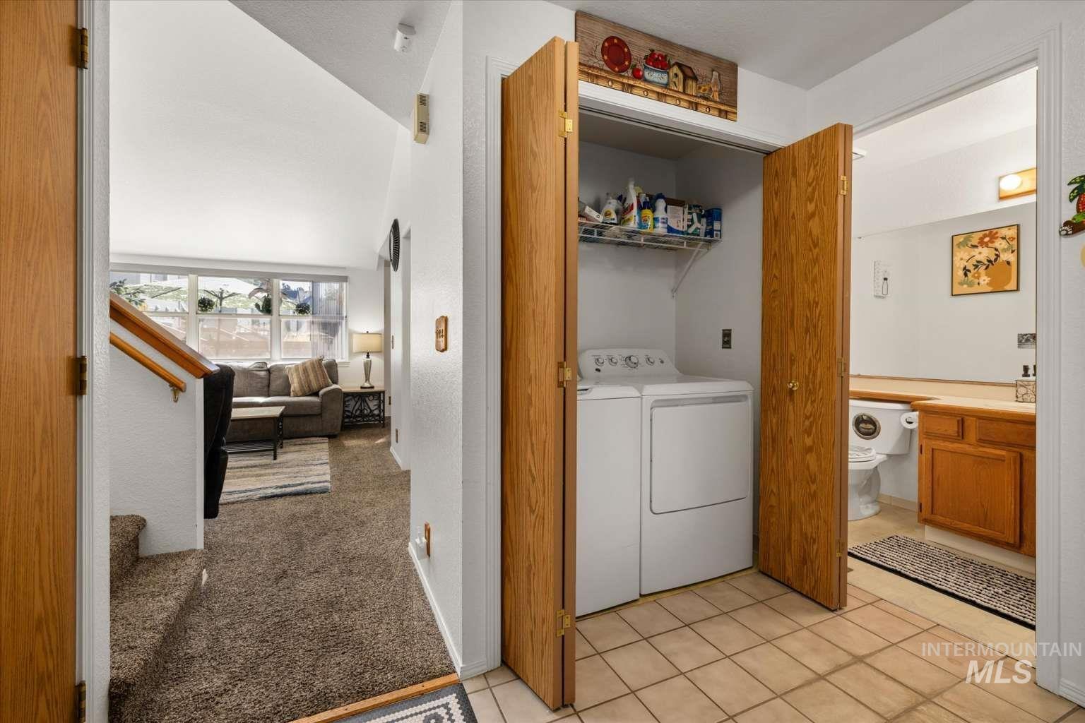 Washroom with light tile patterned floors and separate washer and dryer
