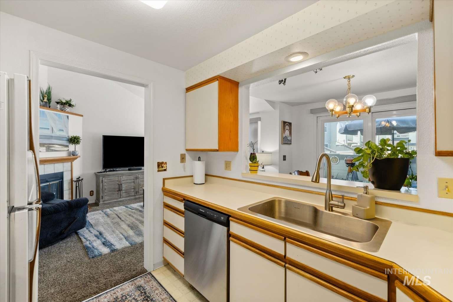 Kitchen with light countertops, dishwasher, a tiled fireplace, and freestanding refrigerator