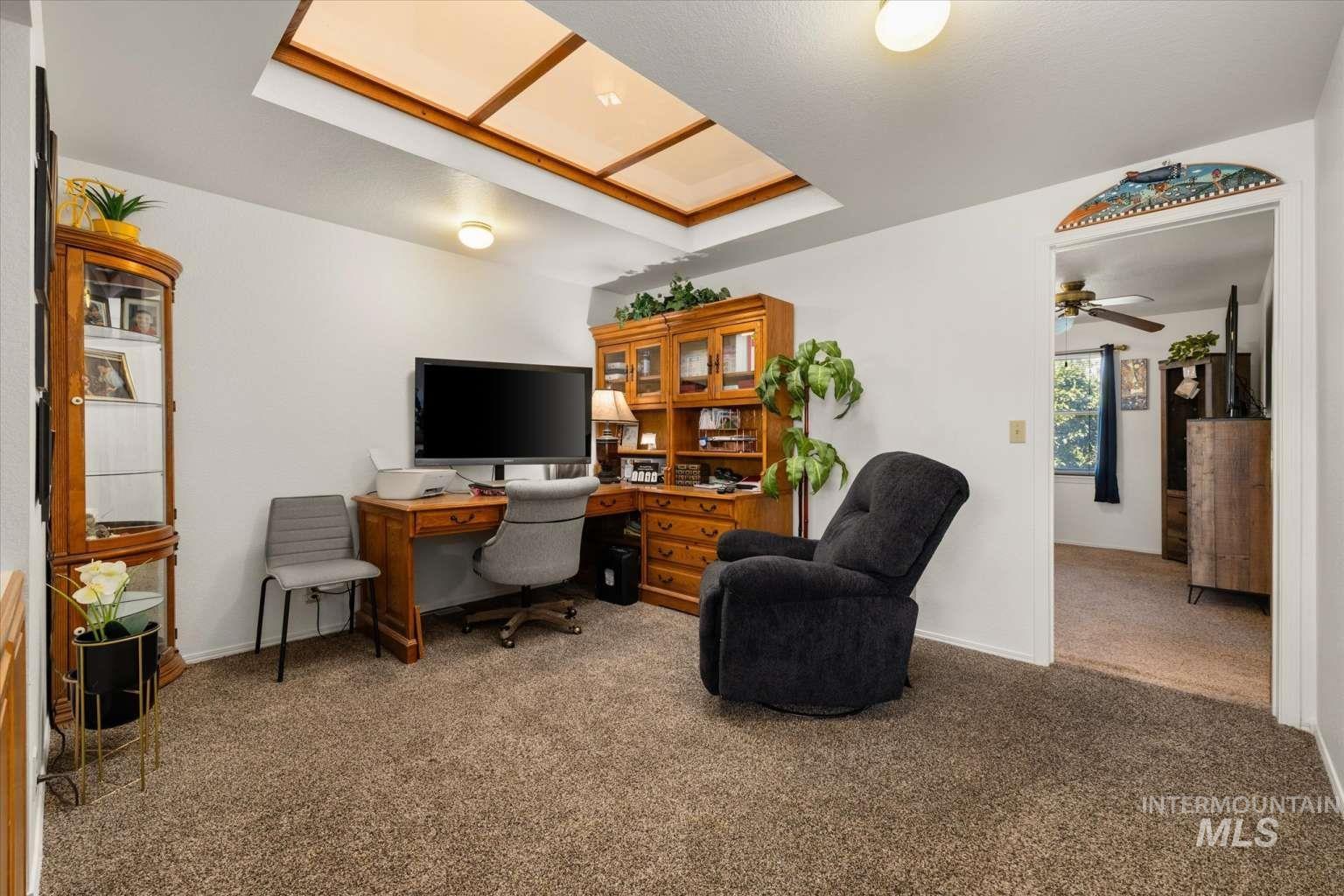 Carpeted office space featuring baseboards and ceiling fan