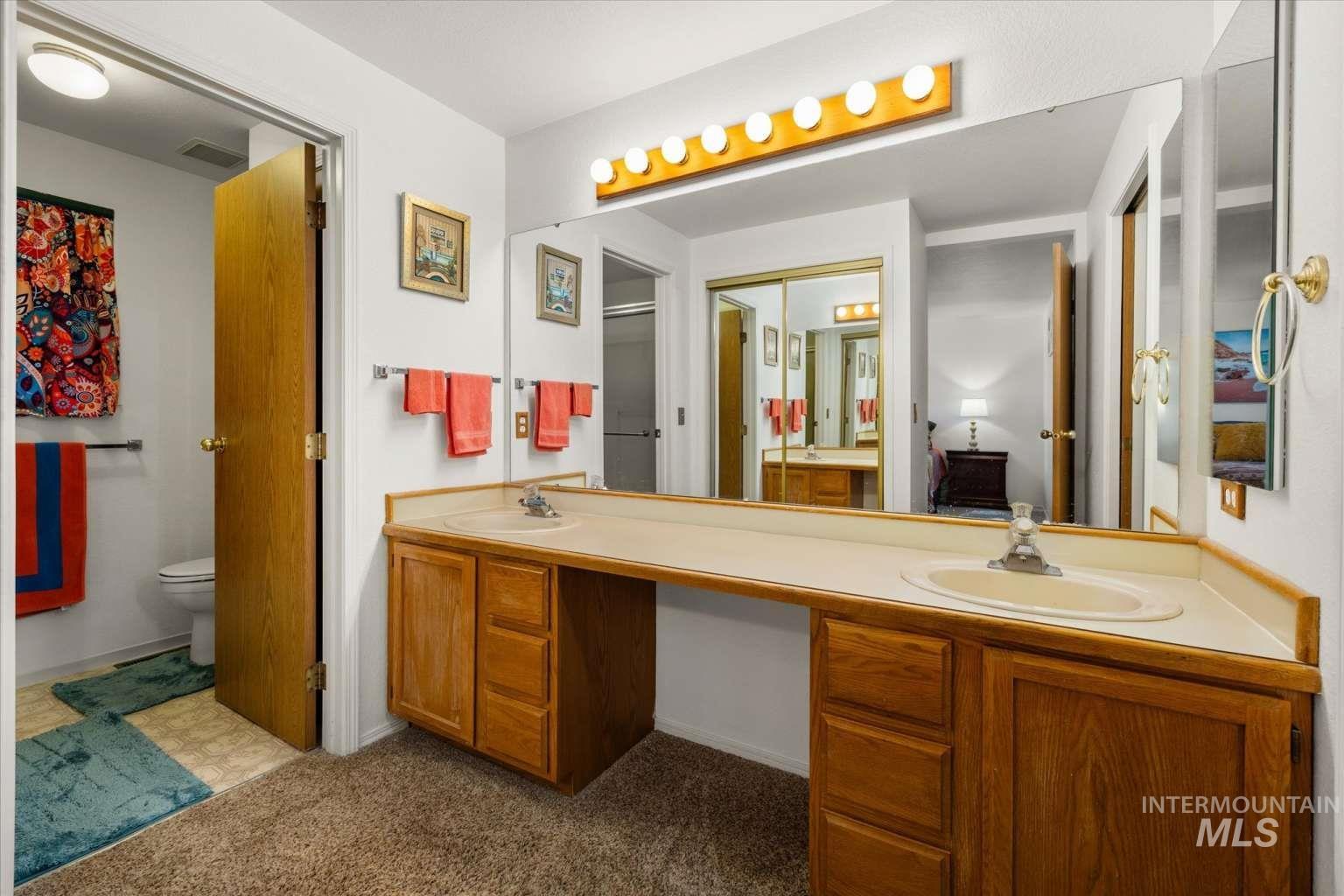 Full bathroom with double vanity and dark colored carpet