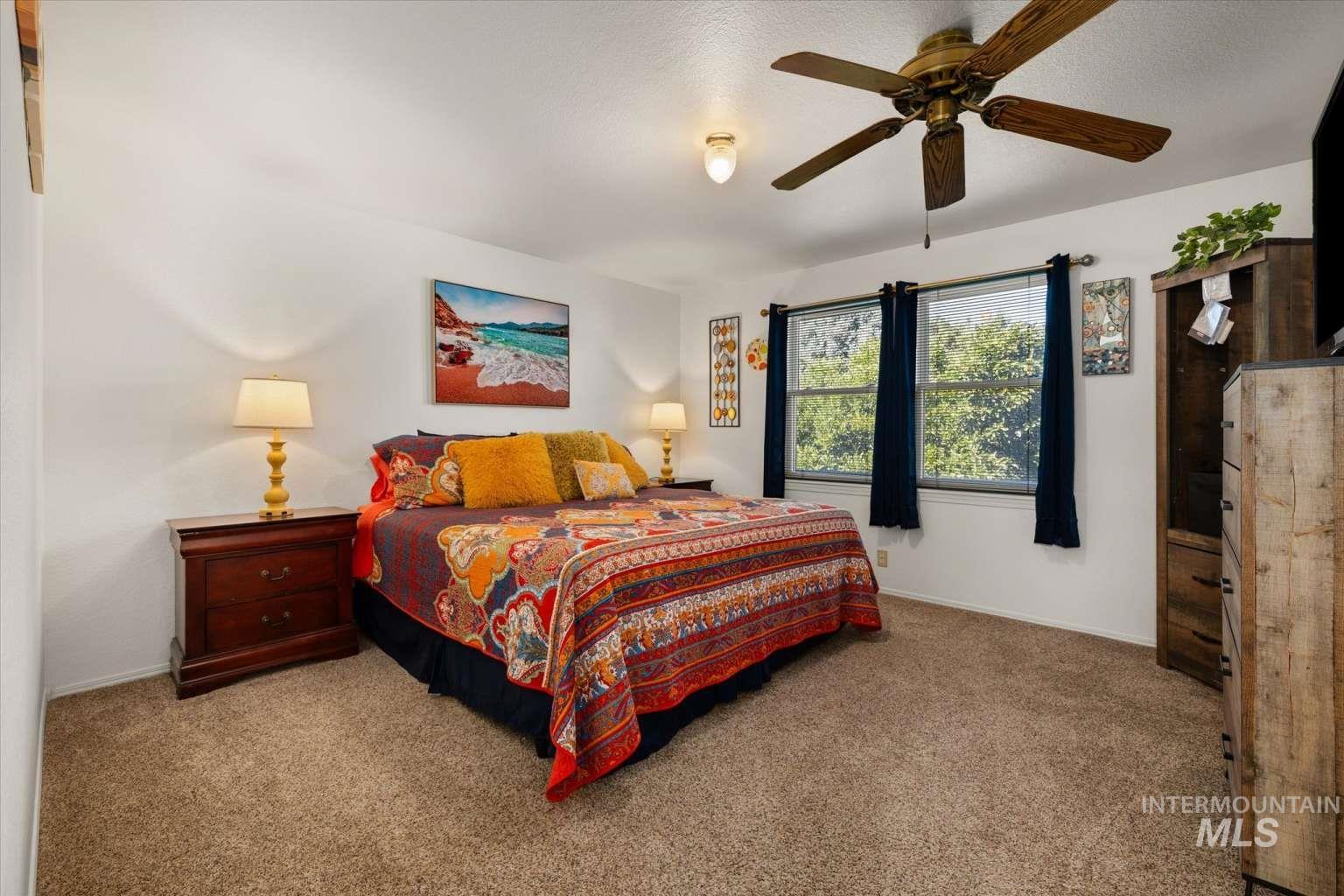 Bedroom with carpet floors, a ceiling fan, and a textured ceiling