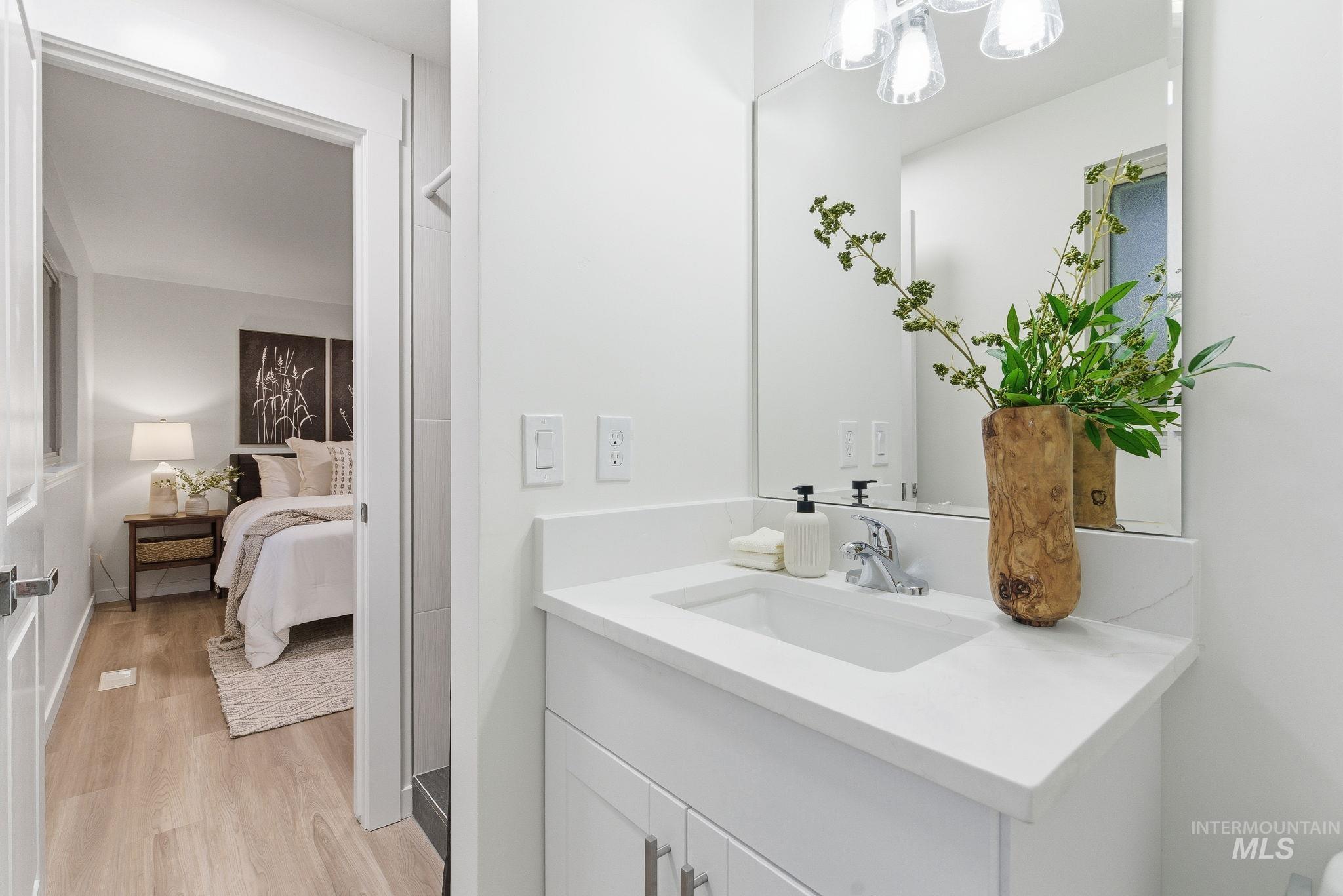 Bathroom with vanity, light wood finished floors, and ensuite bath