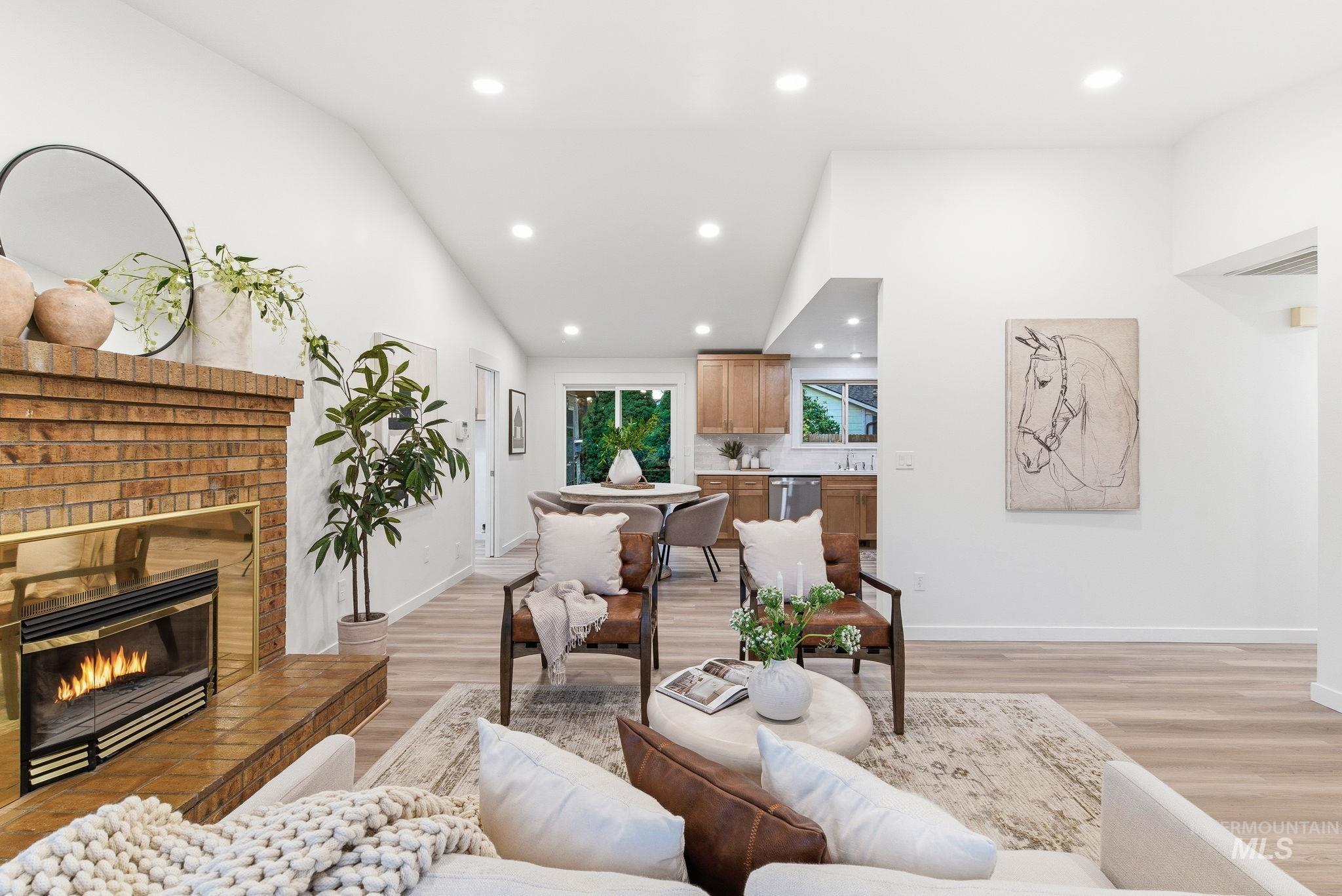 Living area featuring recessed lighting, vaulted ceiling, light wood finished floors, and a fireplace
