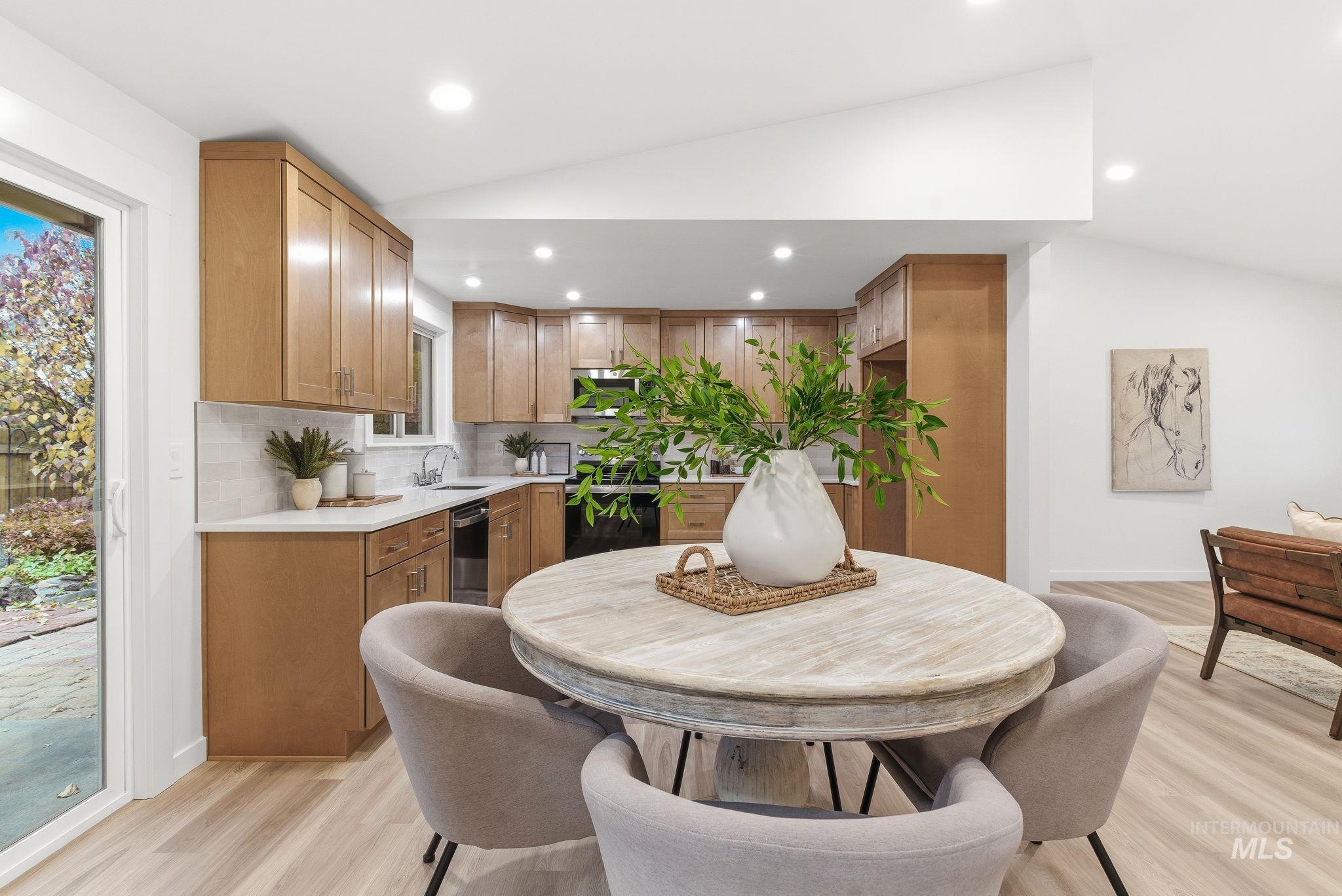 Dining space with lofted ceiling, light wood-style floors, and recessed lighting