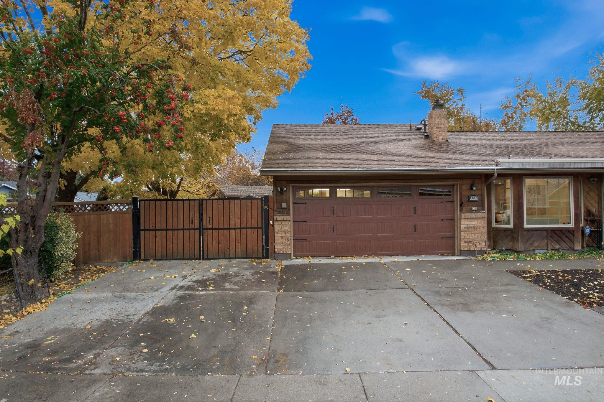 View of front facade featuring roof with shingles, a gate, a chimney, concrete driveway, and a garage