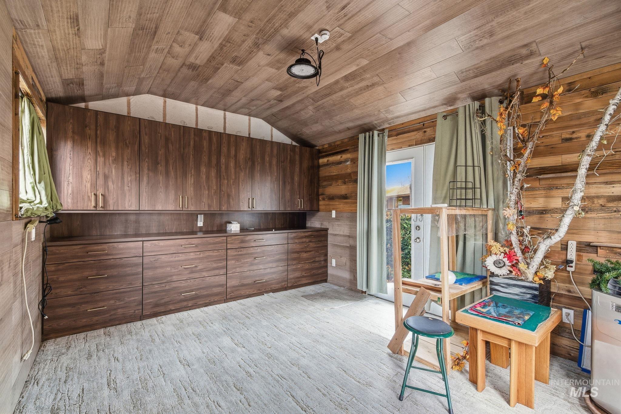 Interior space with wooden walls, wooden ceiling, lofted ceiling, dark brown cabinets, and light wood-style flooring