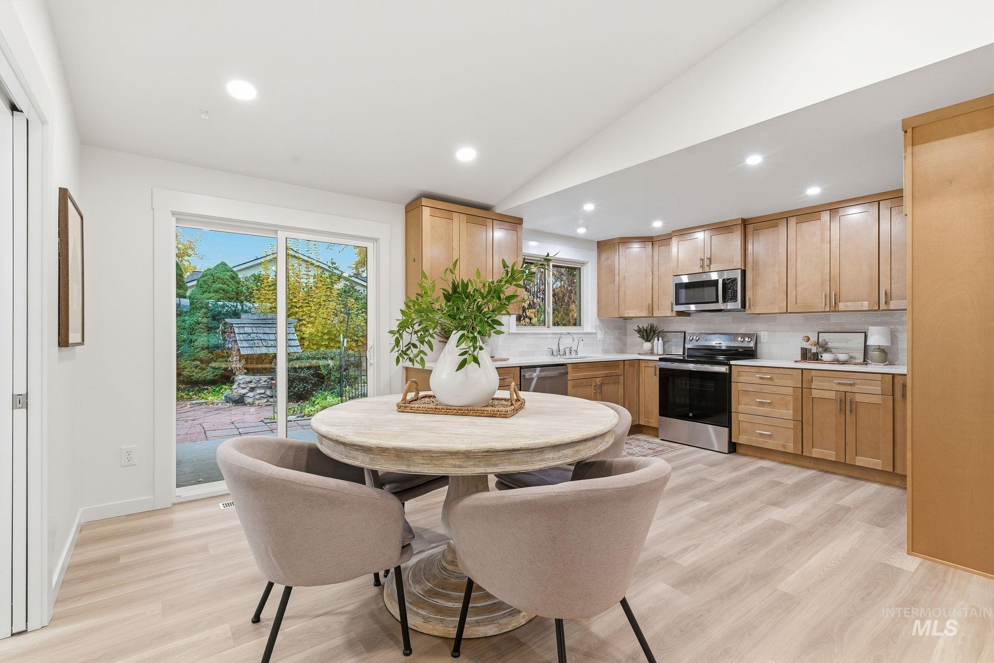 Kitchen featuring recessed lighting, vaulted ceiling, backsplash, appliances with stainless steel finishes, and light wood-type flooring