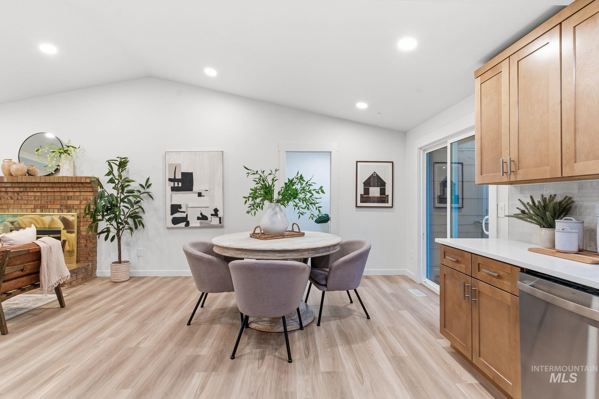 Dining area with recessed lighting, lofted ceiling, light wood-style floors, and a fireplace