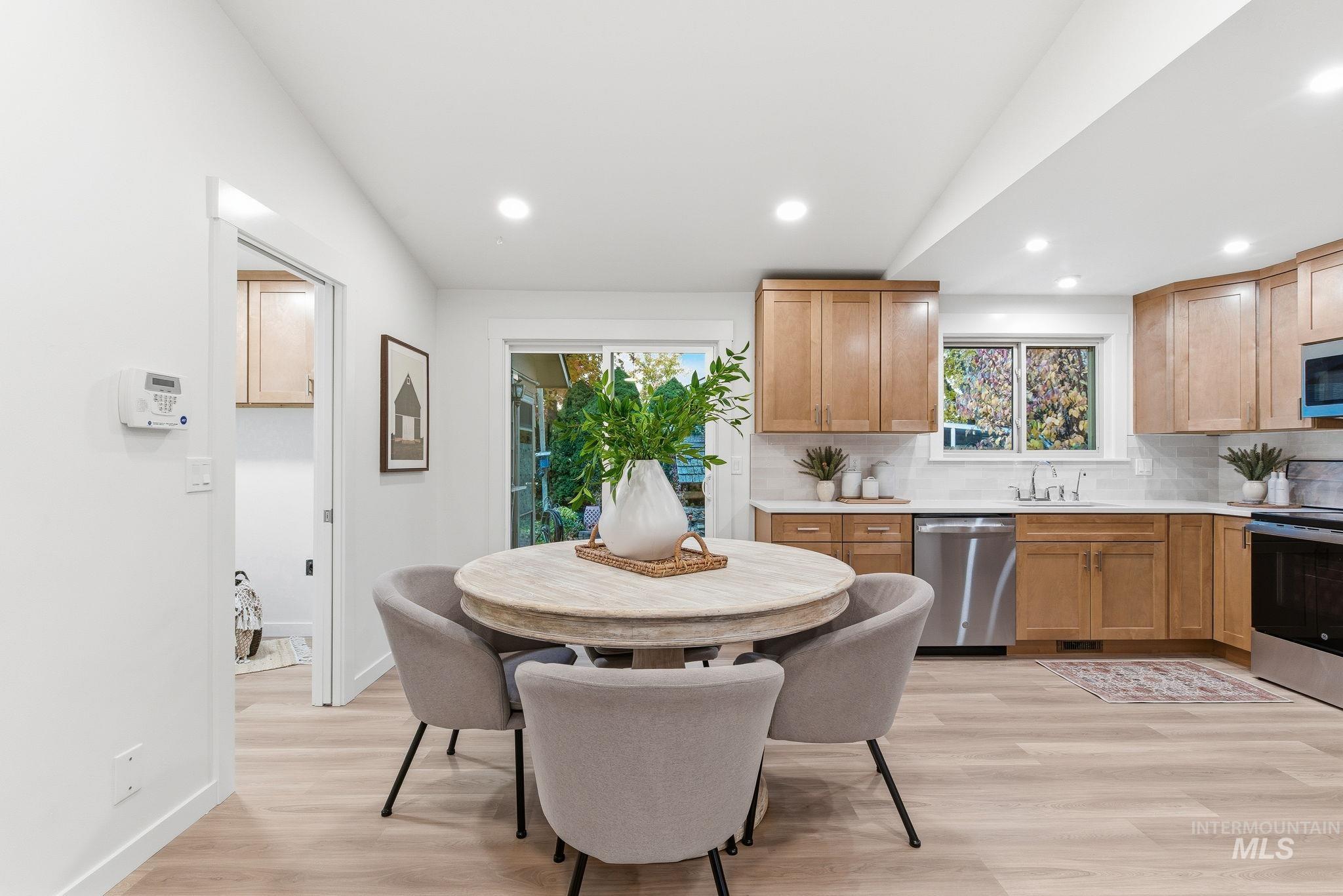 Kitchen featuring decorative backsplash, light wood-type flooring, recessed lighting, stainless steel appliances, and brown cabinetry