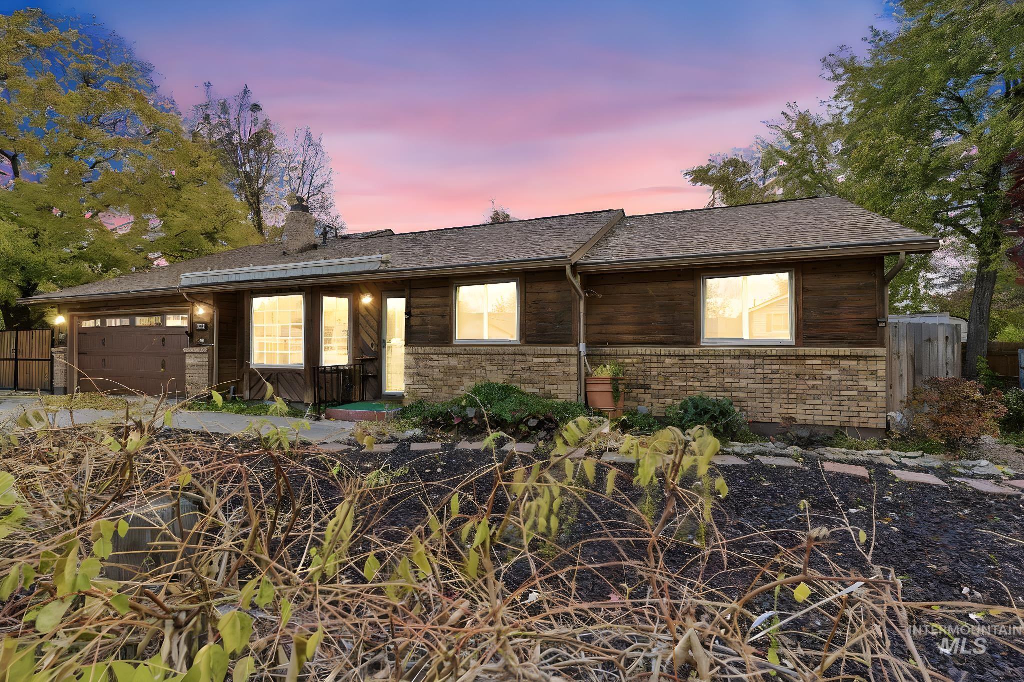 Ranch-style home featuring a chimney, a garage, brick siding, and concrete driveway