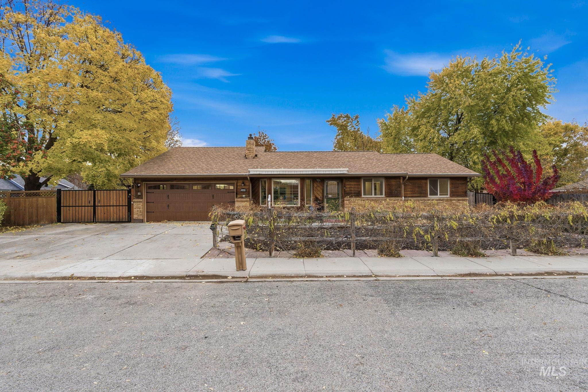 Ranch-style home with a fenced front yard, concrete driveway, a shingled roof, and a garage