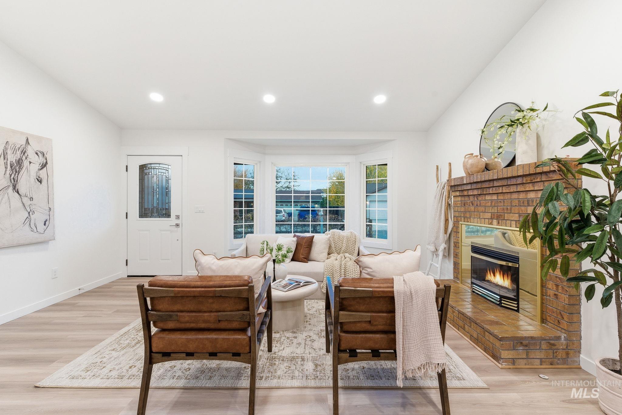 Living area with light wood-style floors, recessed lighting, and a brick fireplace