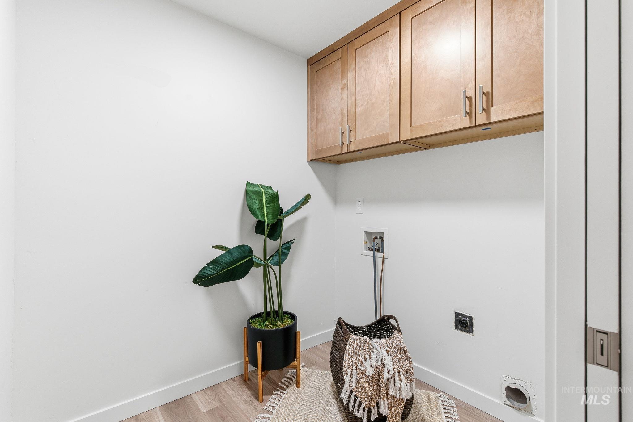 Laundry area featuring cabinet space, light wood finished floors, hookup for a washing machine, and hookup for an electric dryer