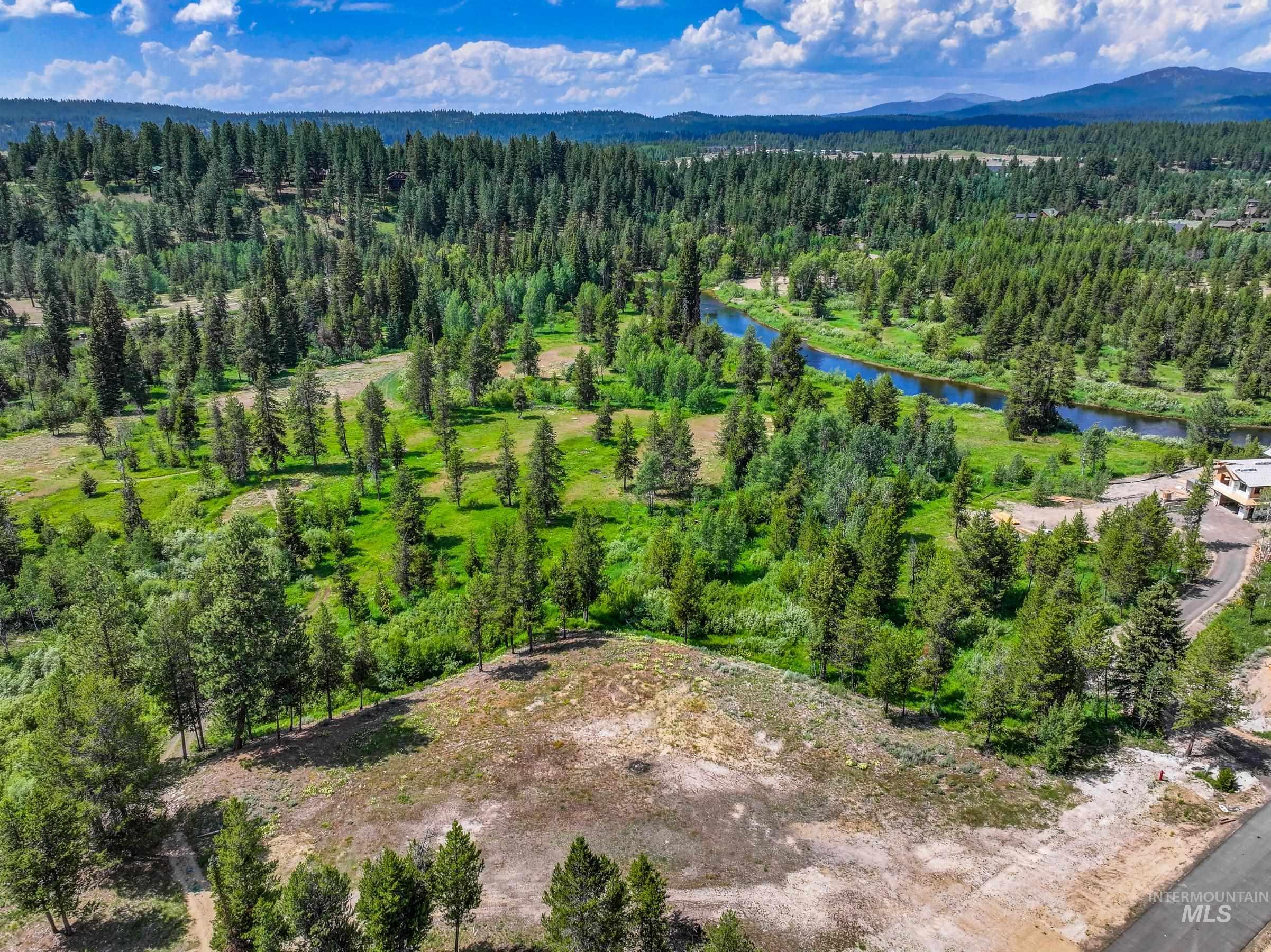 Drone / aerial view of a heavily wooded area and a water and mountain view