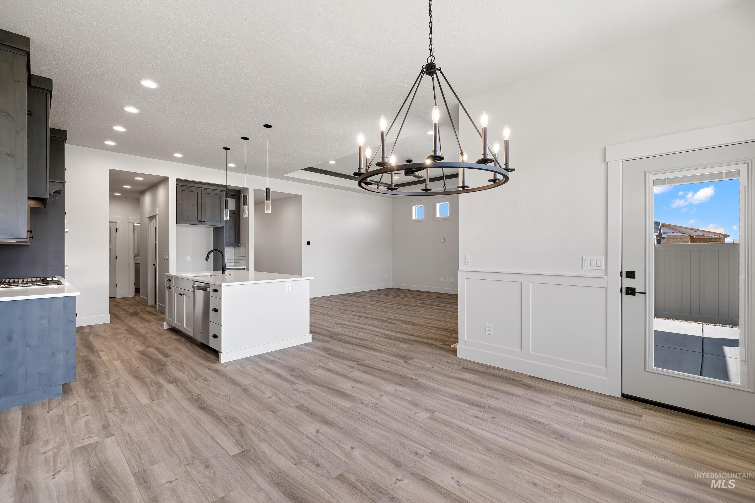 Kitchen with light wood-style floors, decorative light fixtures, open floor plan, recessed lighting, and light stone countertops