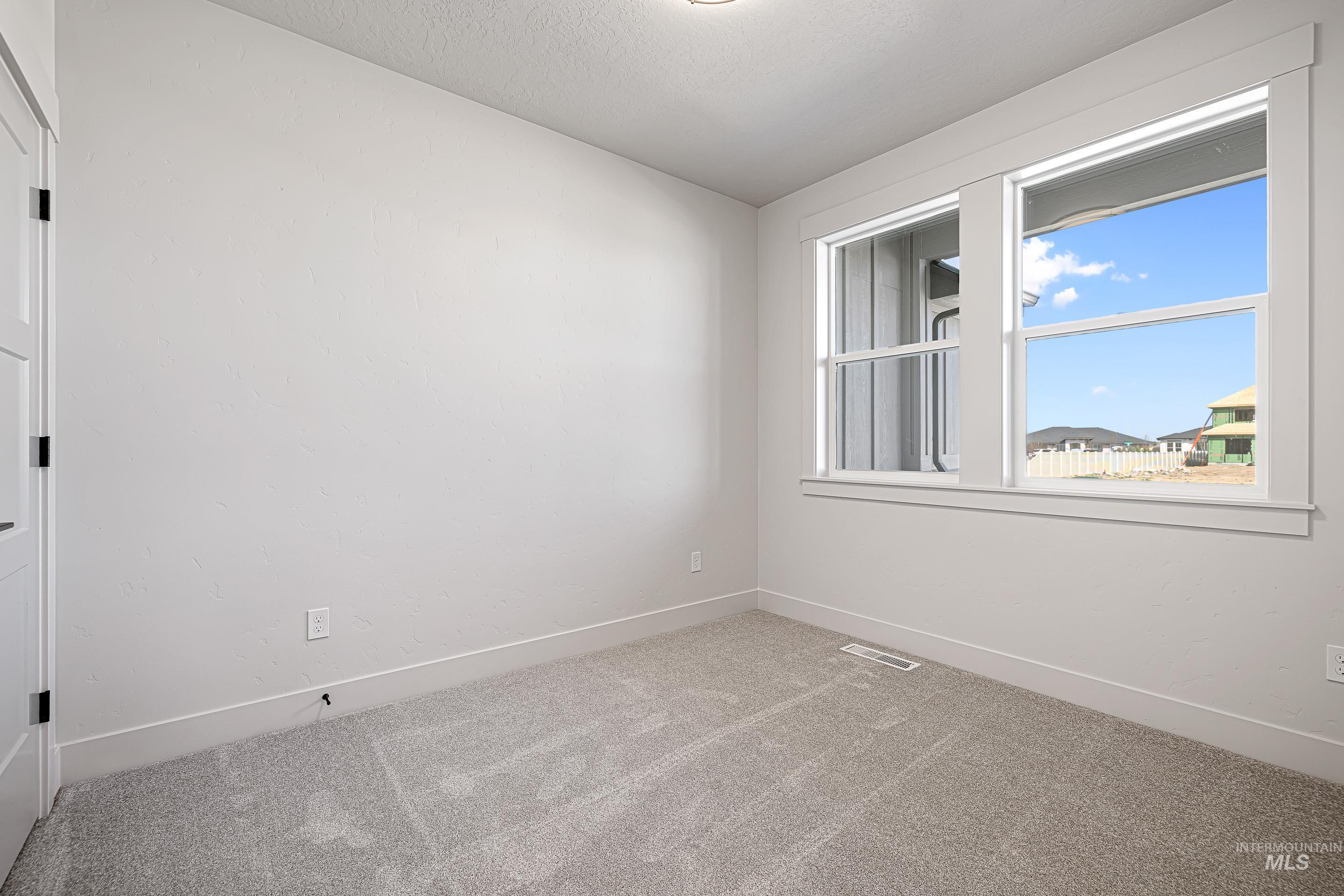 Unfurnished room featuring light carpet and baseboards