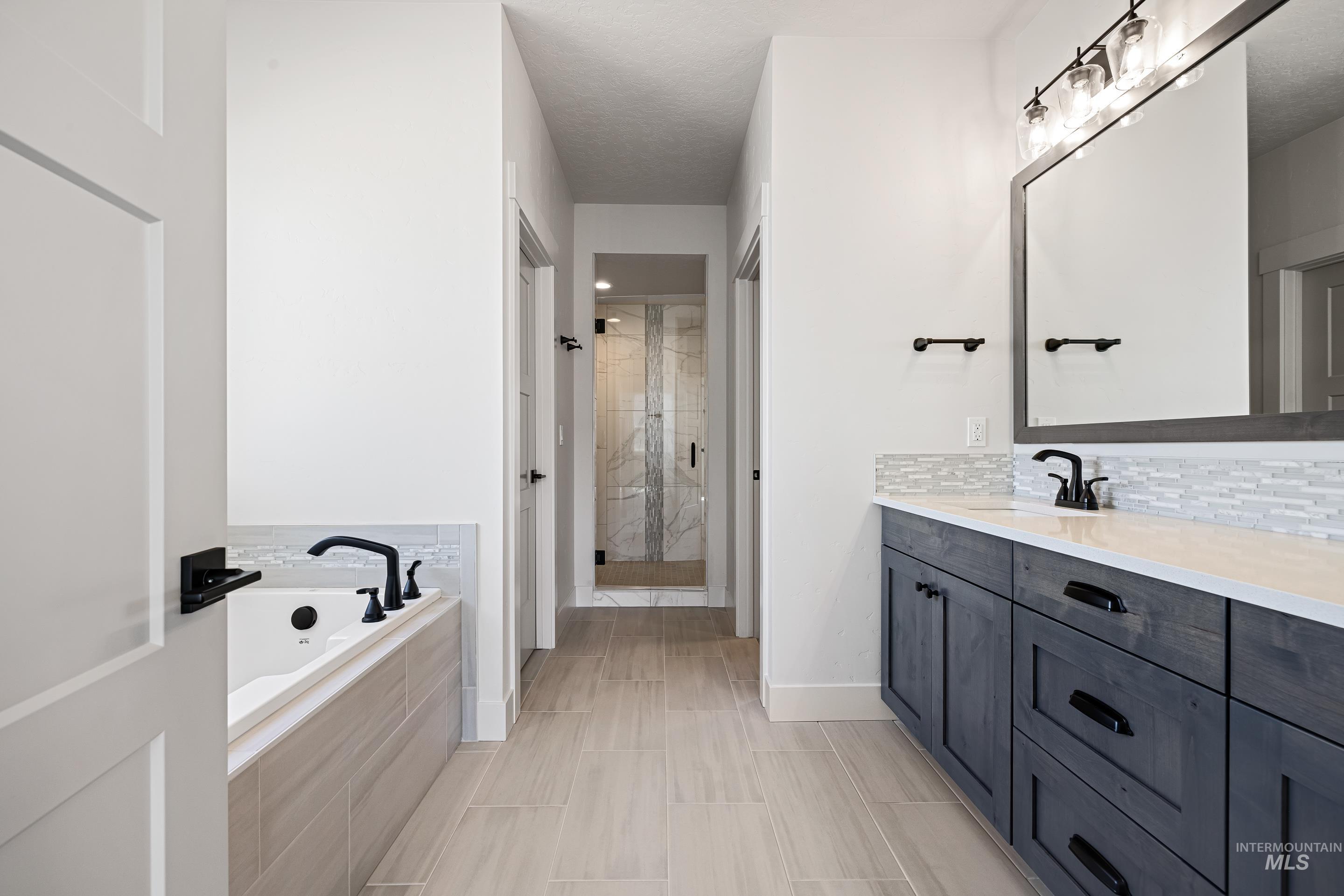 Bathroom featuring vanity, a shower stall, a bath, and decorative backsplash