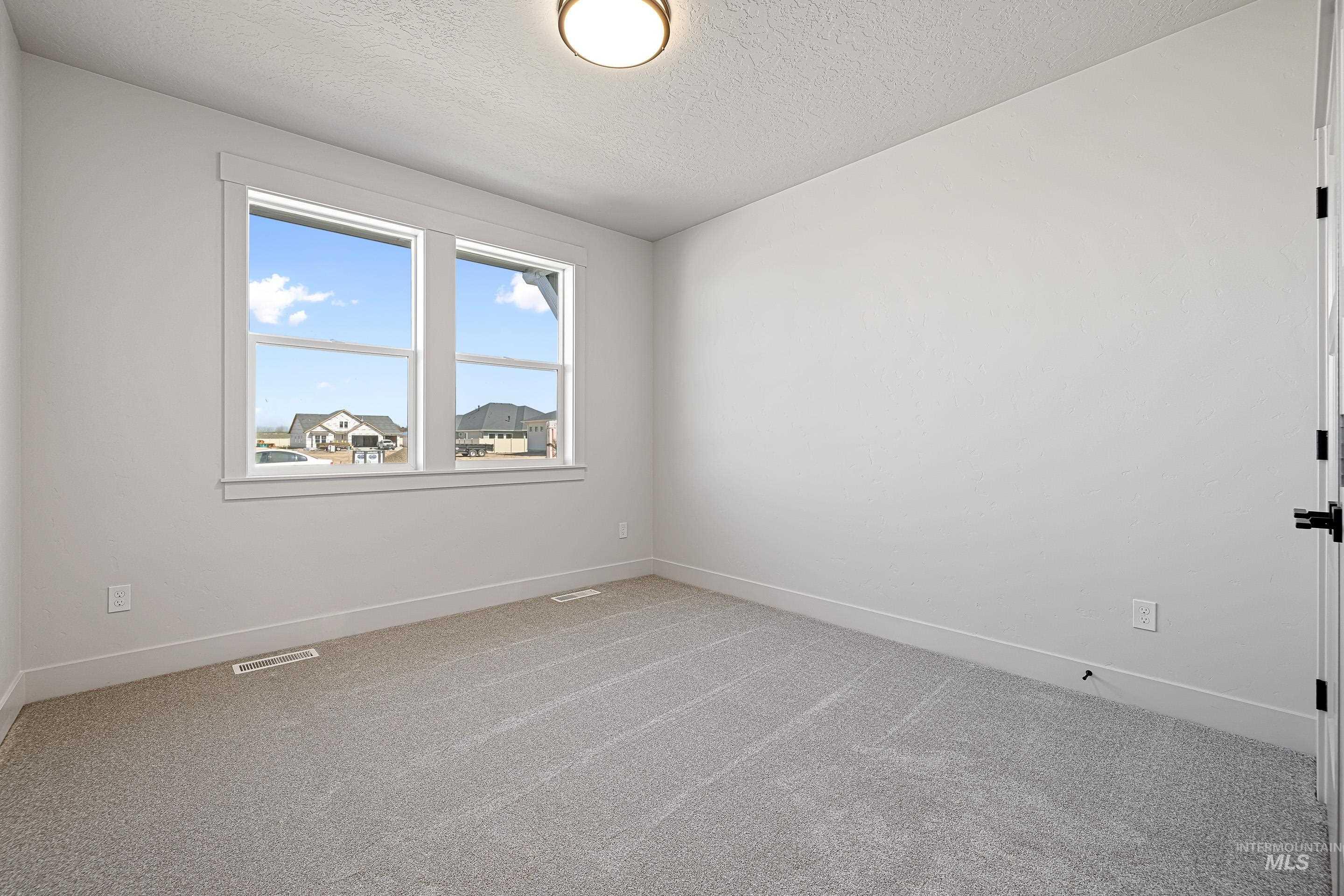Spare room with light carpet and a textured ceiling