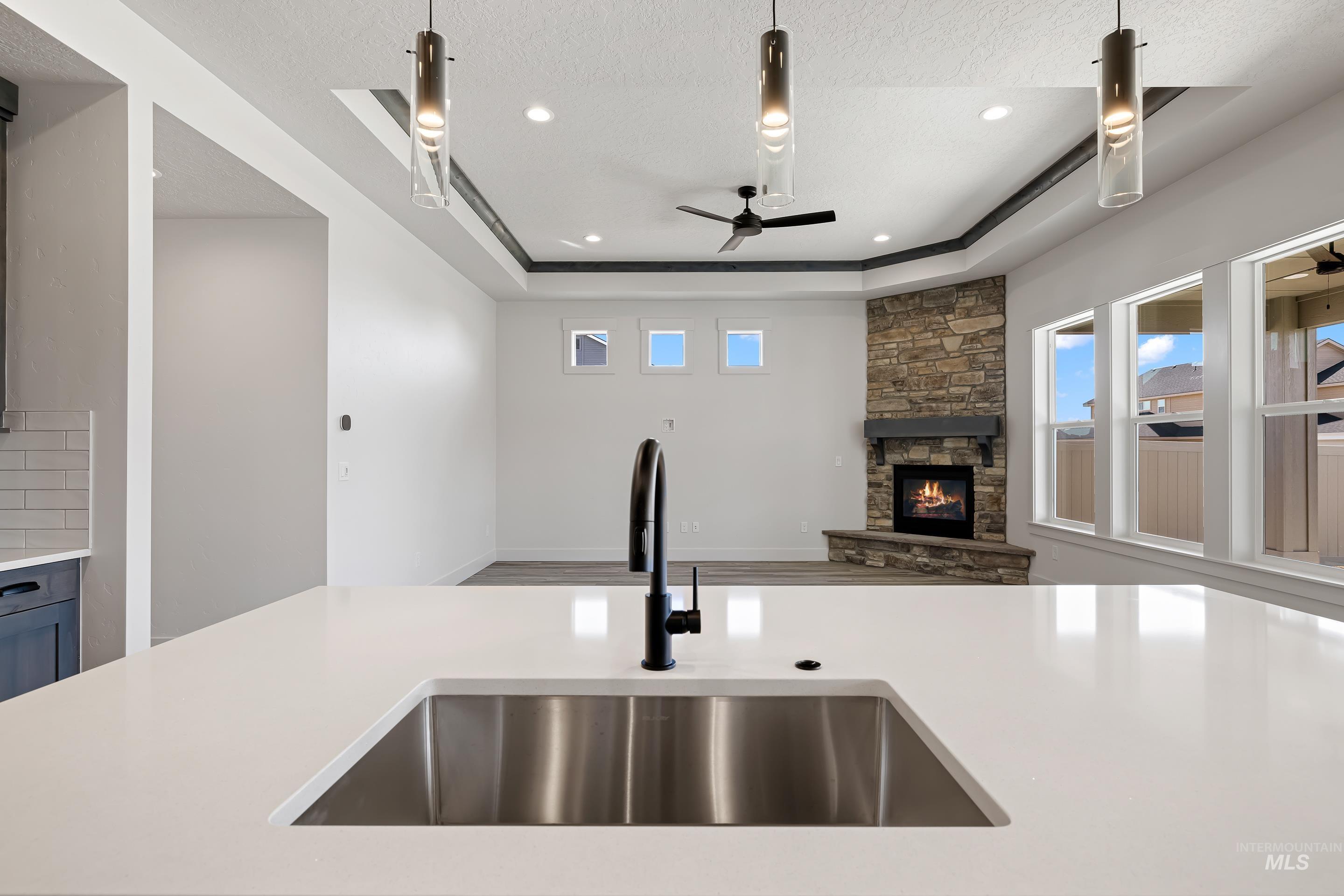 Kitchen with open floor plan, plenty of natural light, a tray ceiling, a fireplace, and a textured ceiling