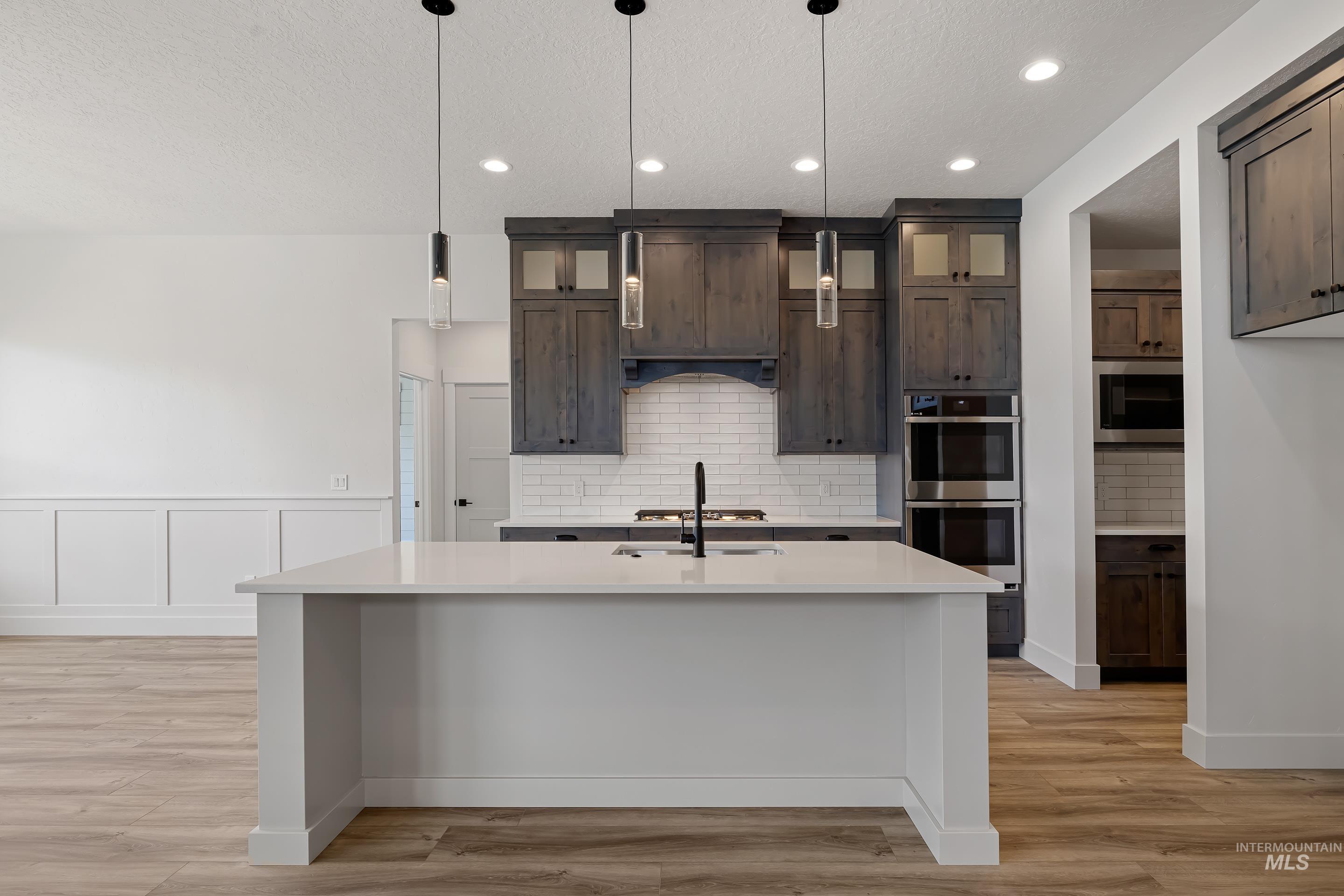Kitchen featuring tasteful backsplash, glass insert cabinets, appliances with stainless steel finishes, light wood finished floors, and recessed lighting