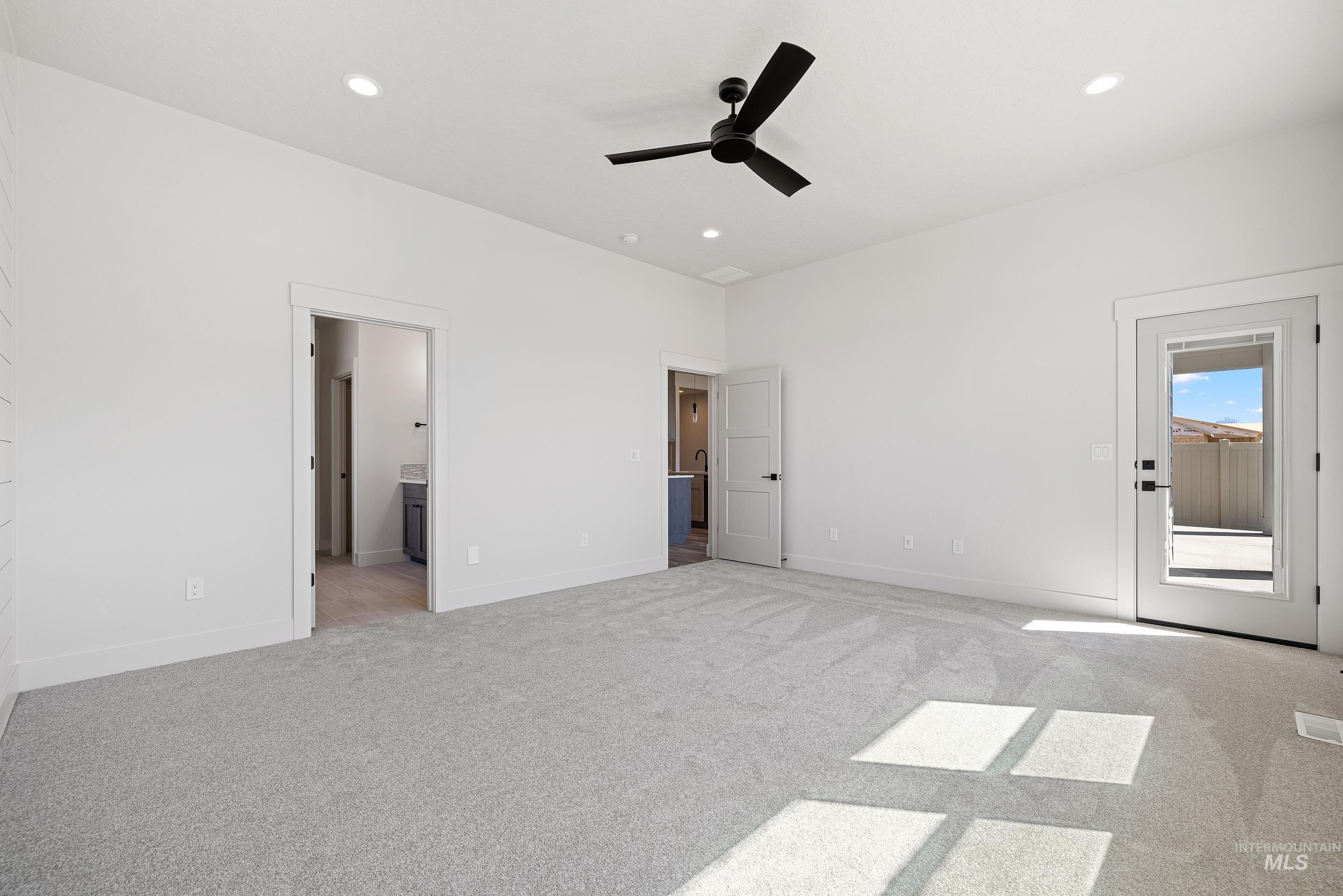 Unfurnished bedroom featuring light colored carpet, ceiling fan, recessed lighting, ensuite bathroom, and access to exterior