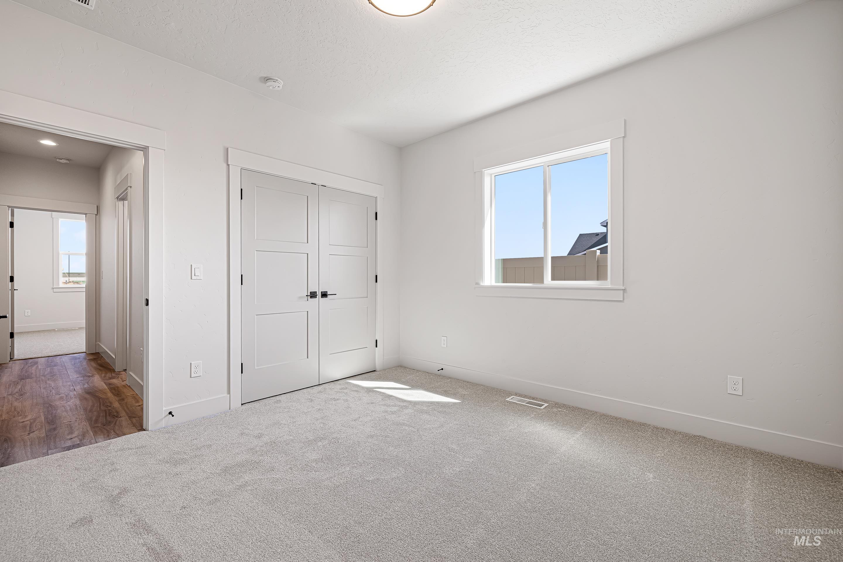 Unfurnished bedroom with carpet, a closet, and a textured ceiling