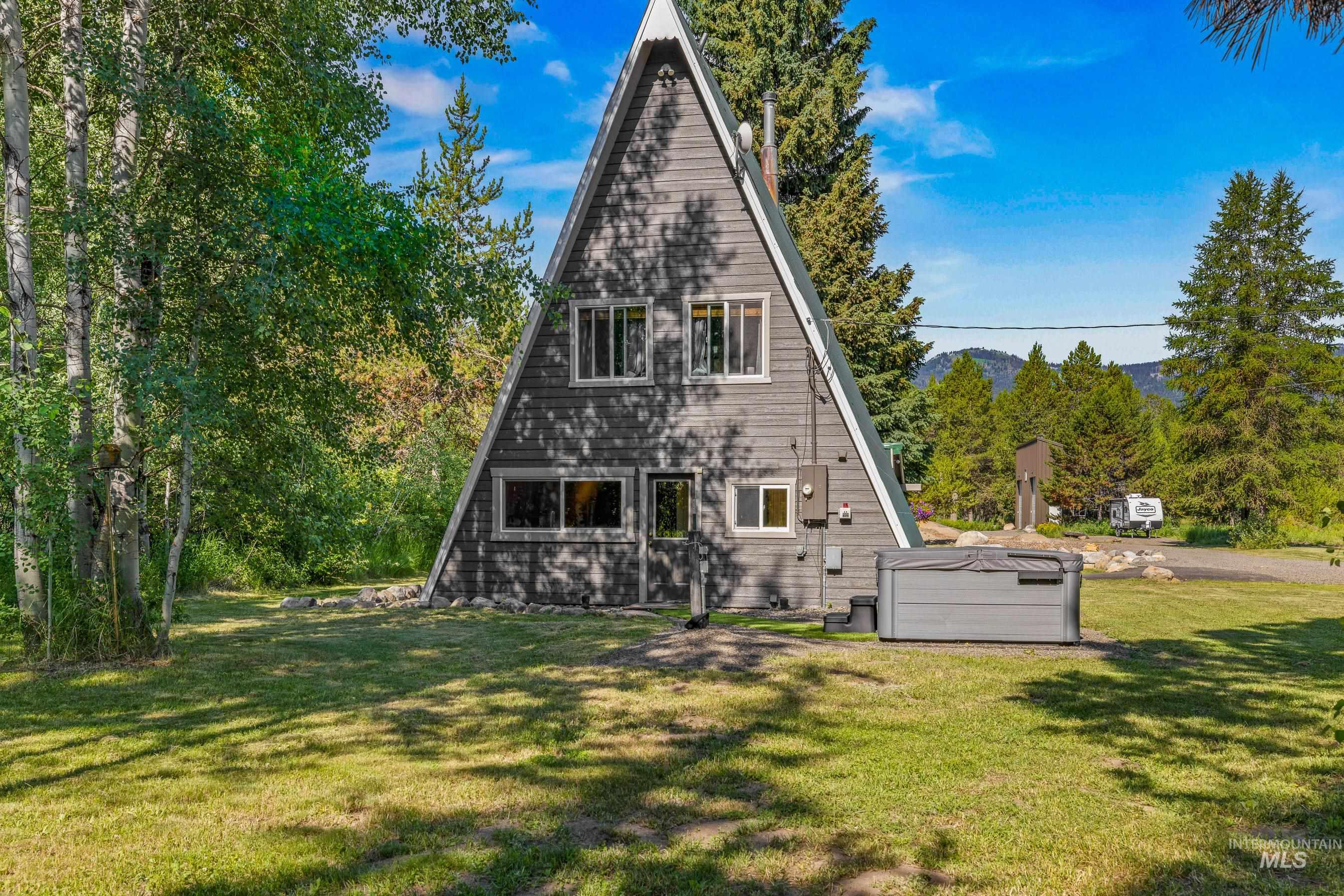 Back of property with a lawn and a hot tub