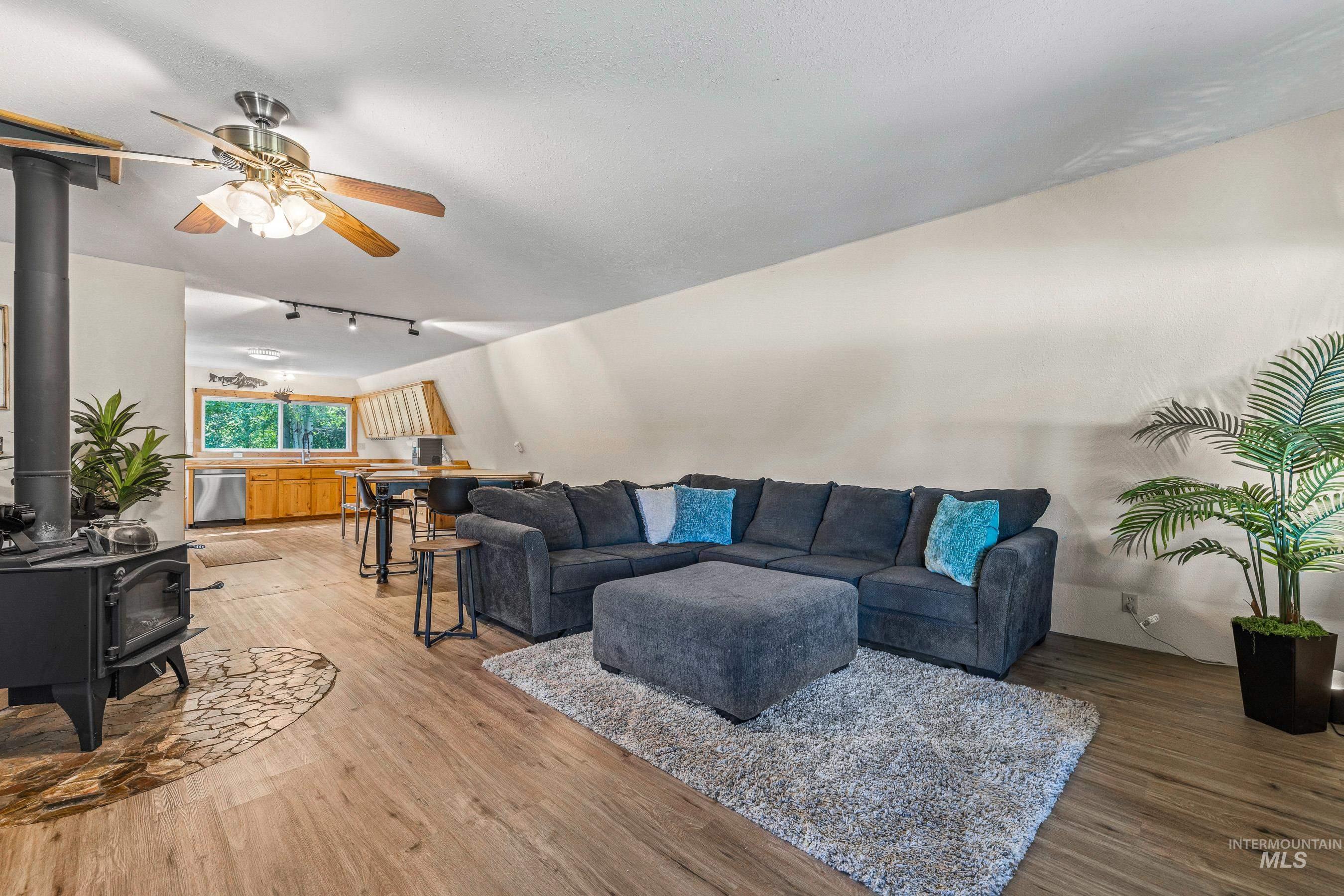 Living room with a wood stove, a ceiling fan and LVP flooring.
