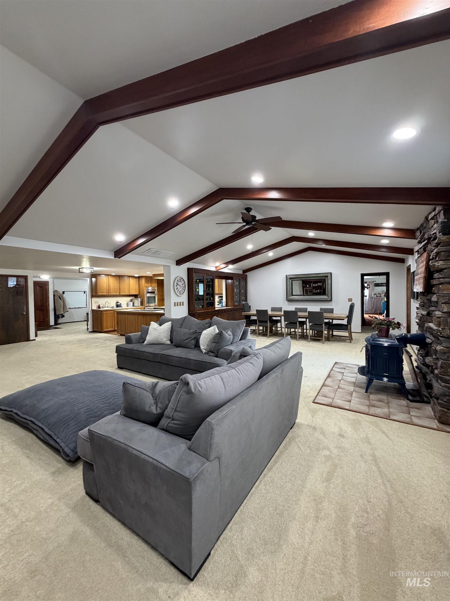 Open-concept living area featuring vaulted ceilings with exposed wood beams and recessed lighting