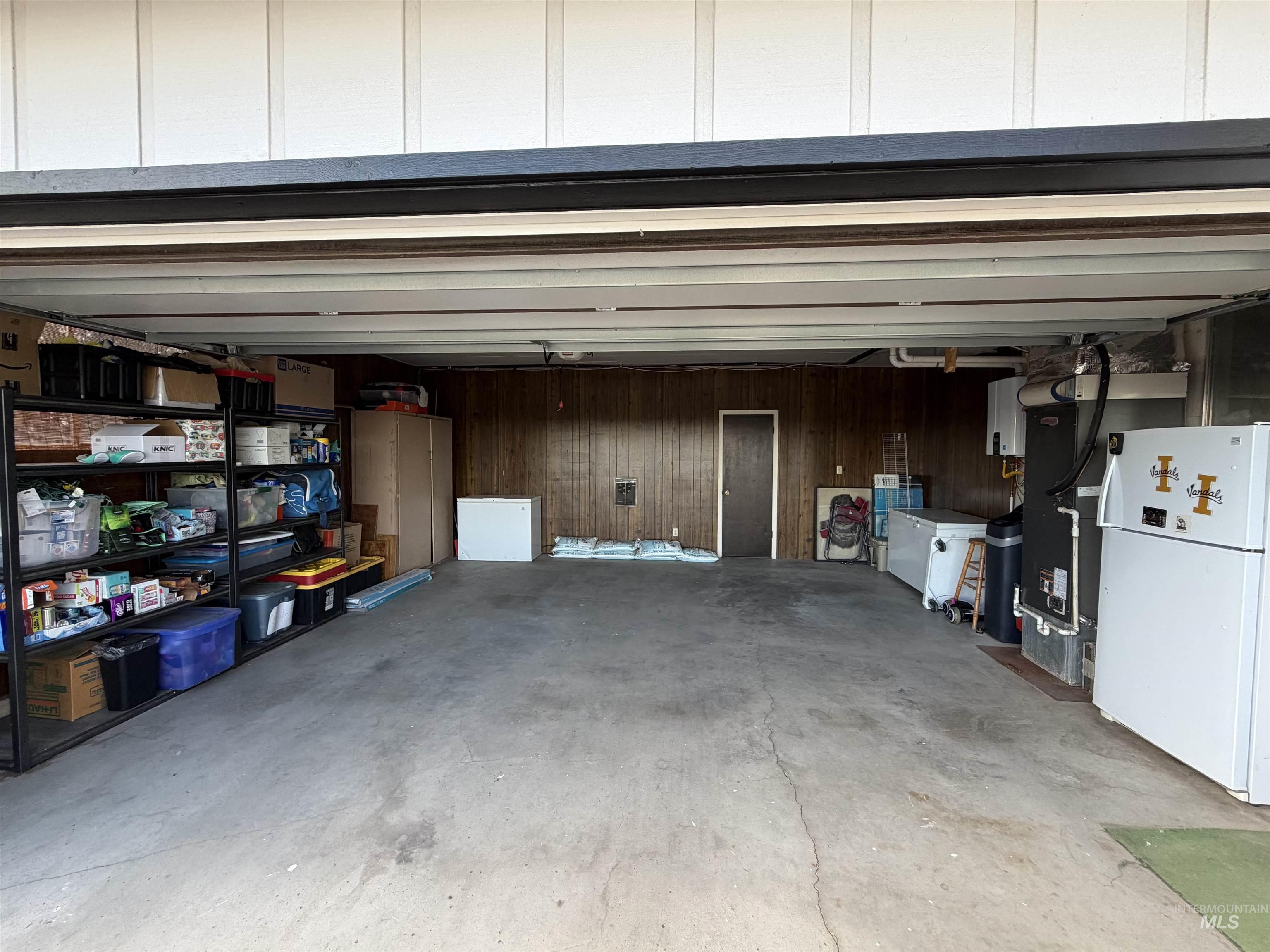 Spacious garage with concrete flooring and wood paneling