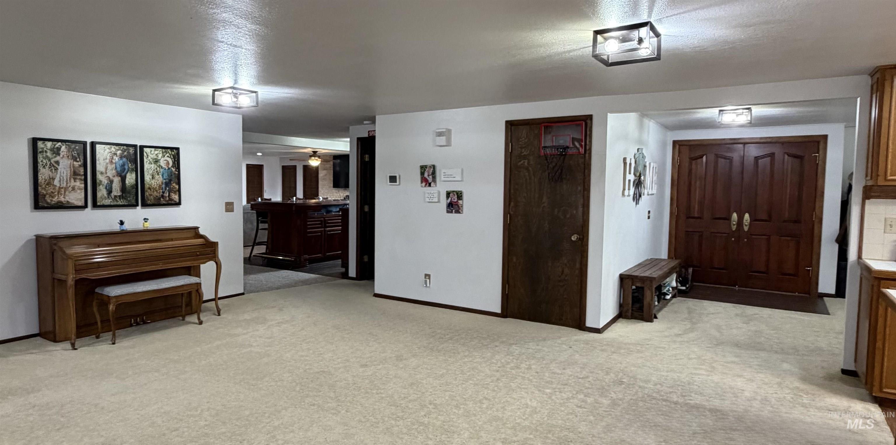 Expansive carpeted area featuring a double-door entry with wood panels, recessed ceiling lights, and wood trim details
