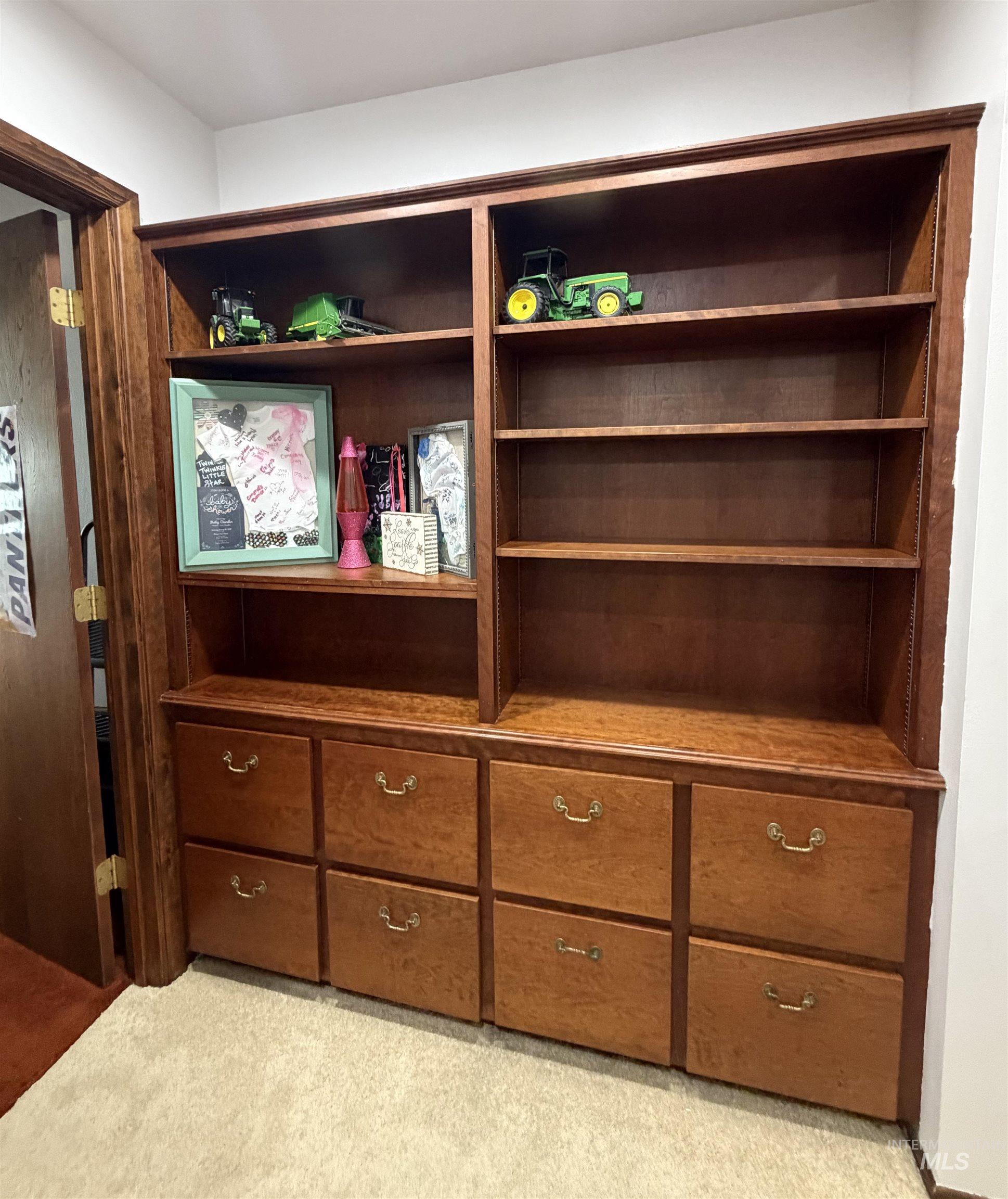 Built-in wood cabinetry featuring multiple shelving units and integrated lower drawers with brass-finish hardware