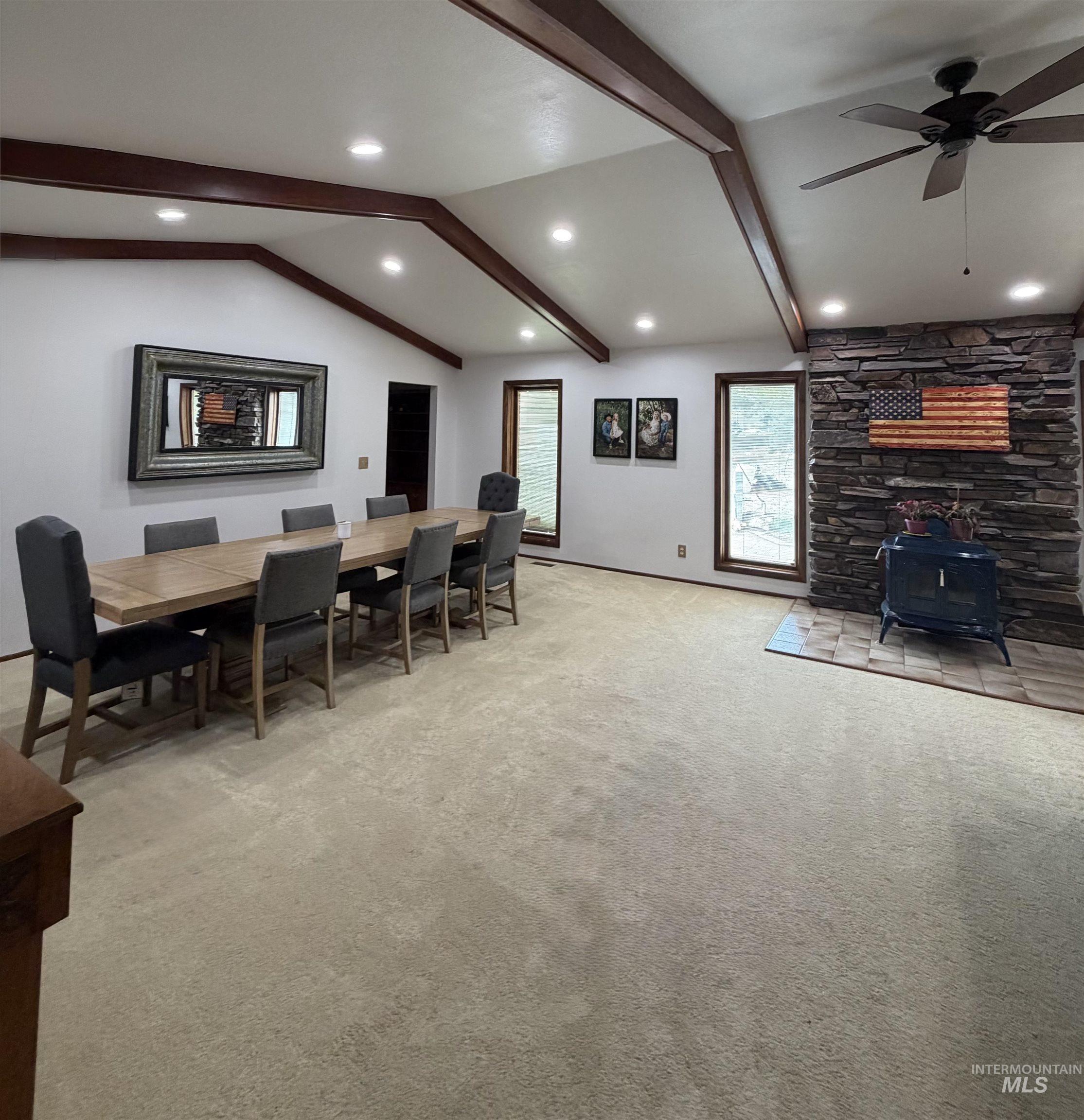 Spacious living area featuring a vaulted ceiling with exposed wood beams and recessed lighting