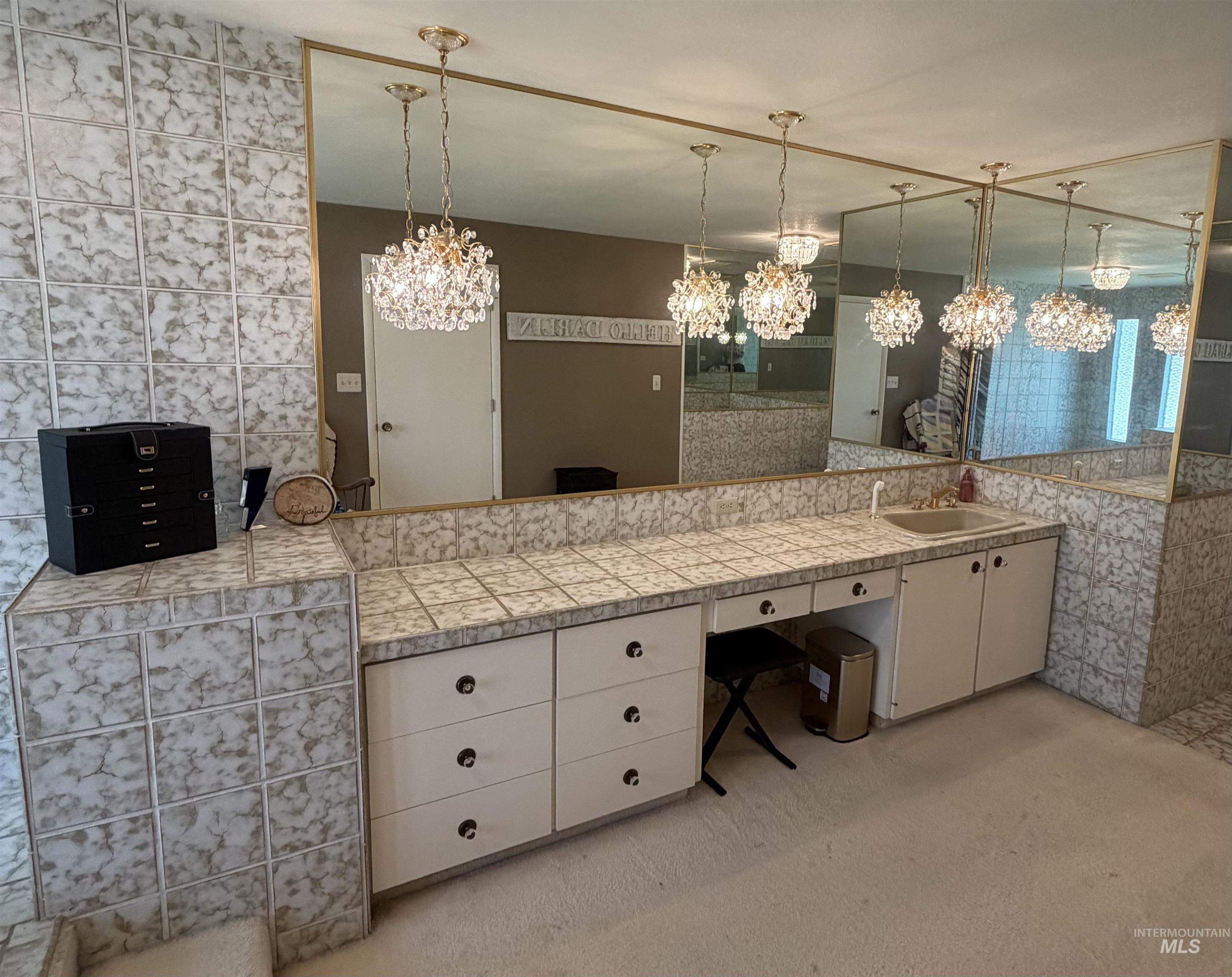 Vanity area featuring an integrated sink, extensive counter space with tiled surfaces, and multiple base cabinets with drawers