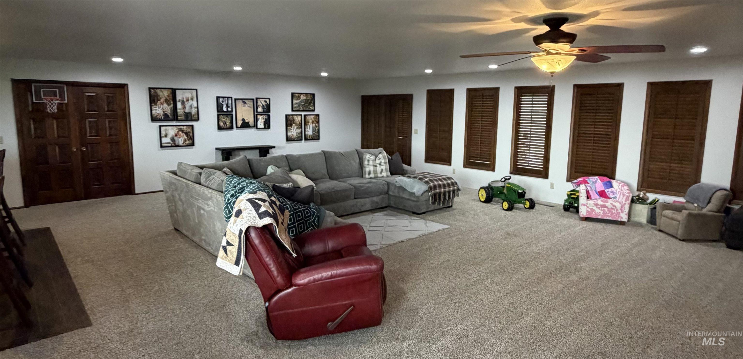 Expansive living area featuring plush carpet flooring, recessed lighting, and a ceiling fan